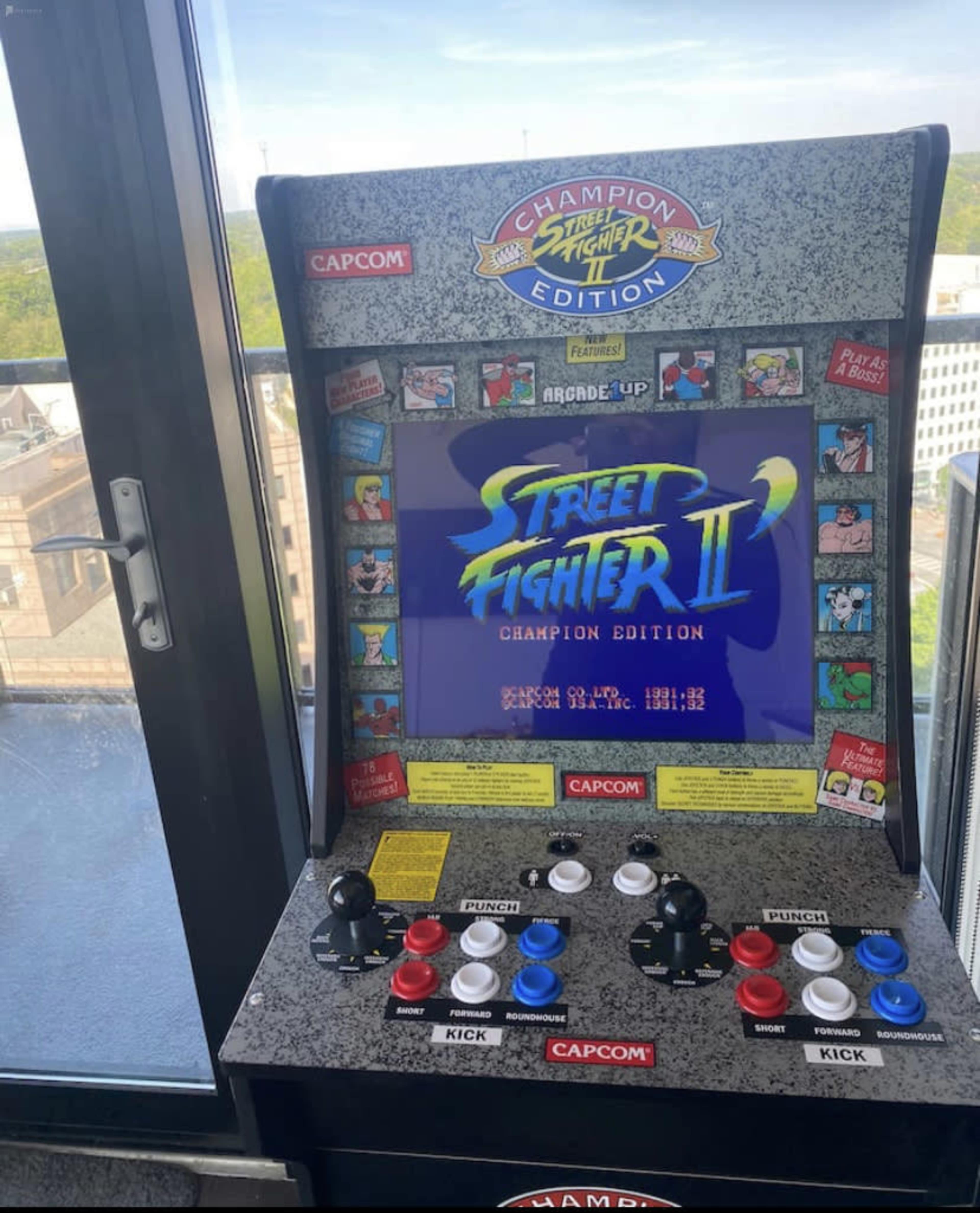 The image shows a classic arcade game cabinet for "Street Fighter II: Champion Edition" with control buttons and a vibrant screen displaying the game title.