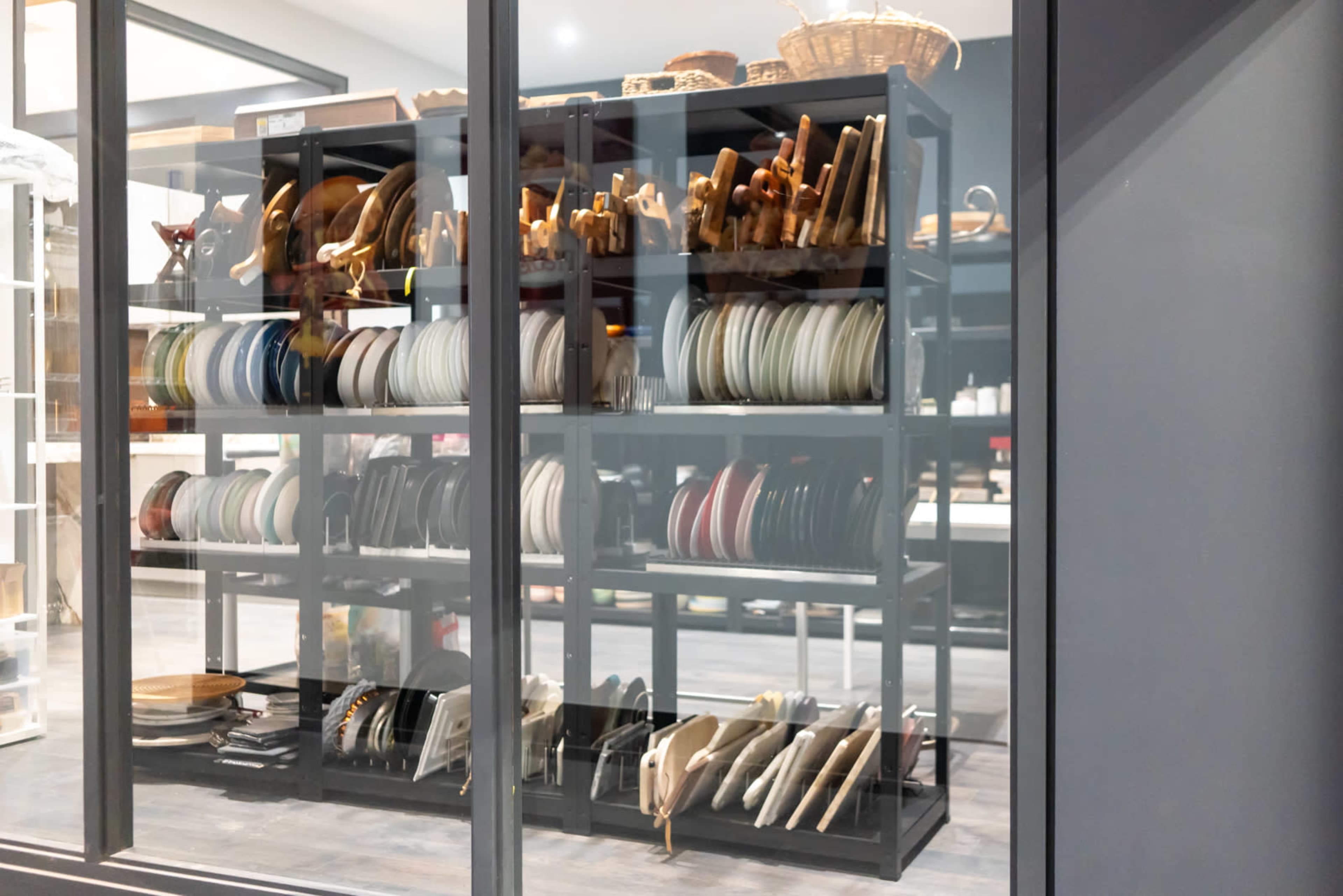 A set of shelves displays various kitchenware, including stacked plates, wooden utensils, and decorative trays.