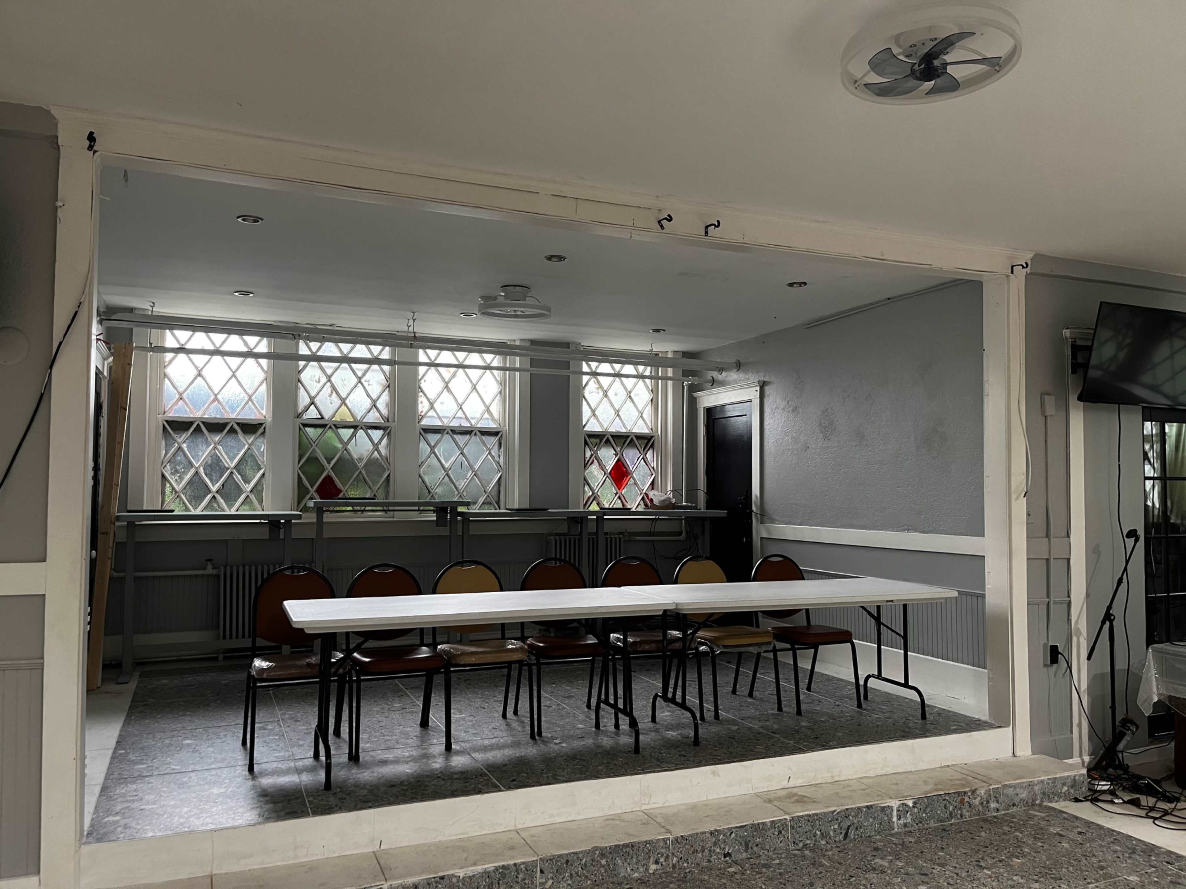 A meeting room with a long table and several chairs arranged around it, illuminated by natural light from windows.