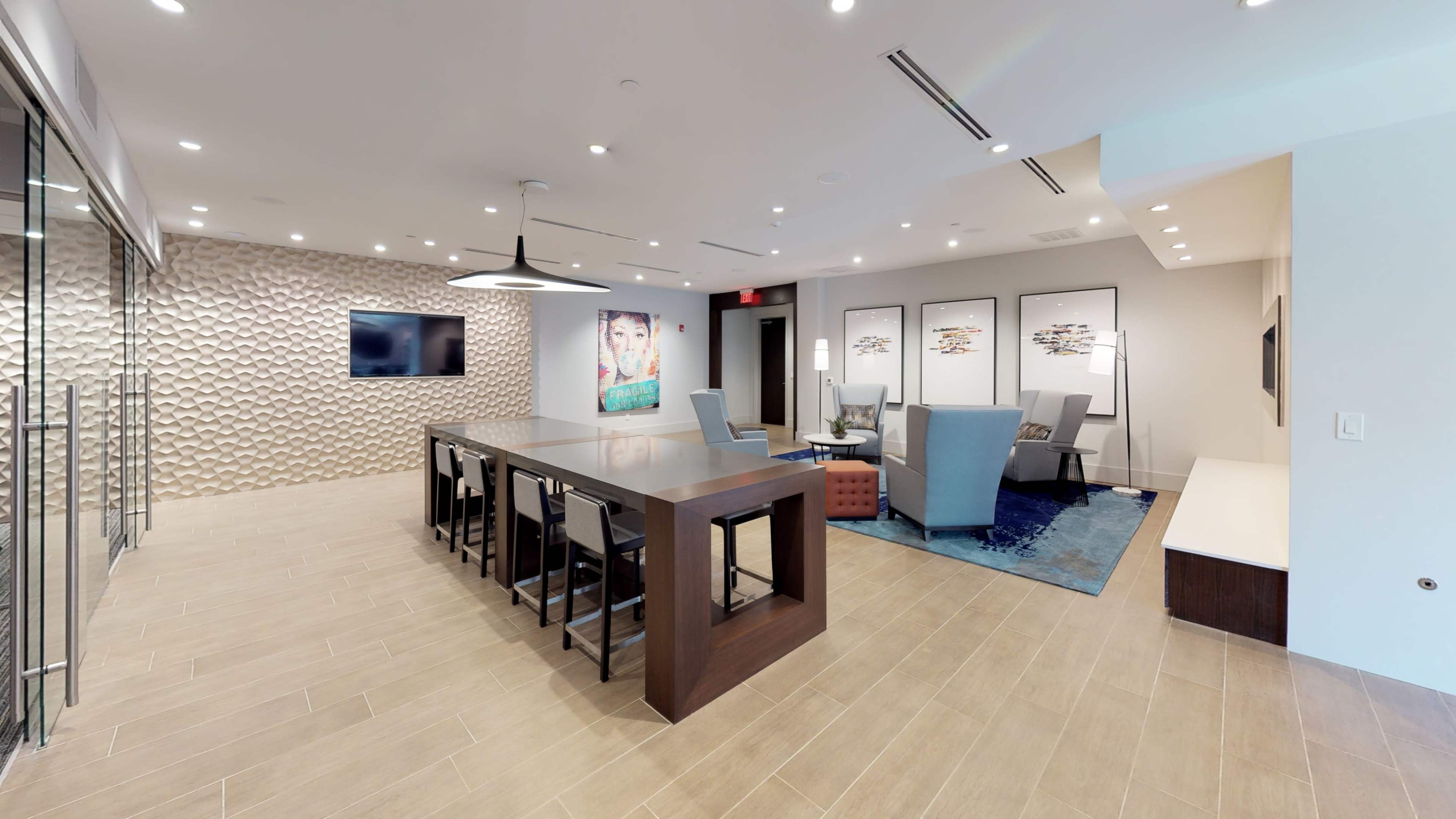 A modern conference room with a long wooden table, surrounding chairs, a wall-mounted television, and art on the walls.