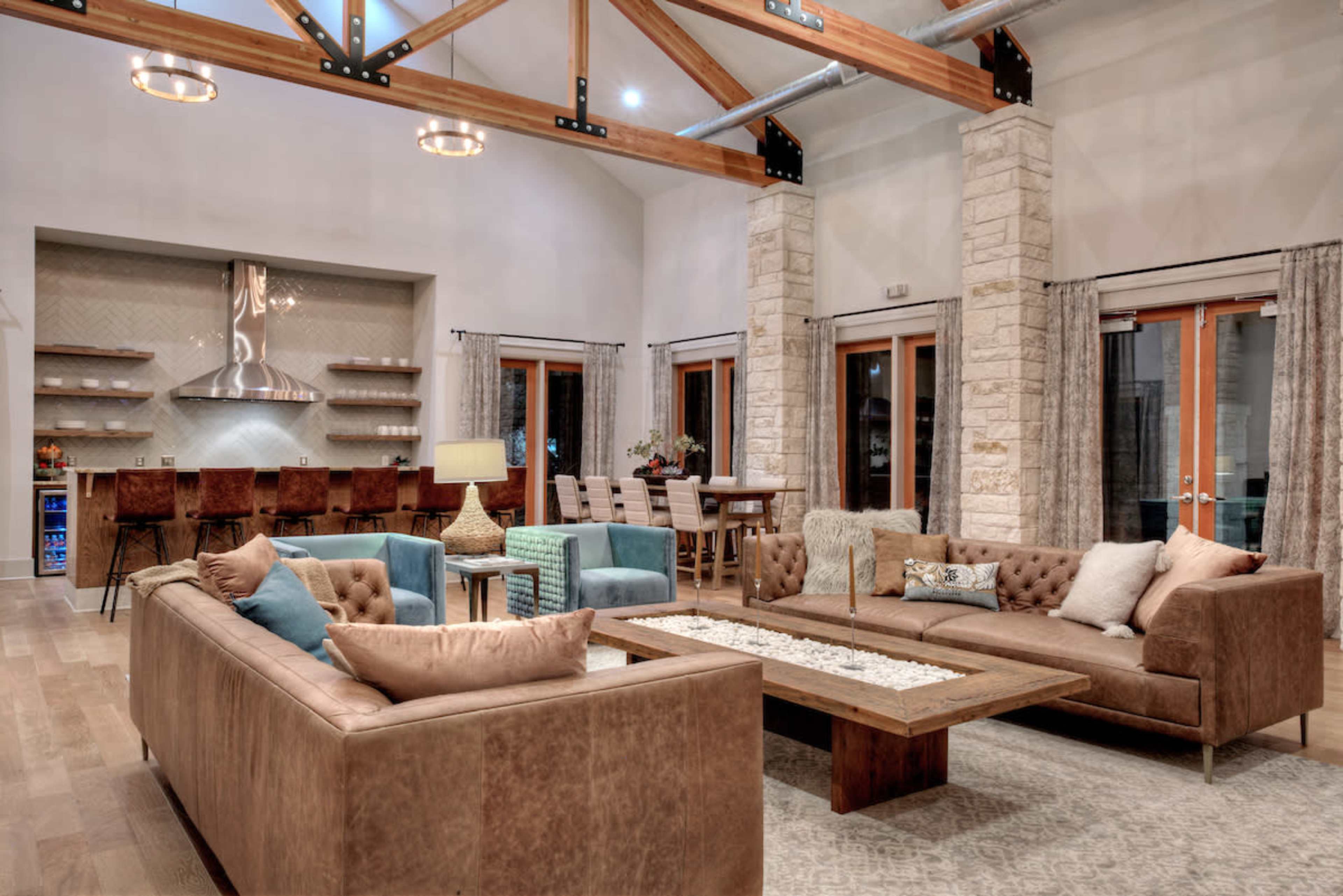 The open-concept living area features a mix of leather and upholstered furniture, a wooden coffee table, and a dining space with bar seating in the background.