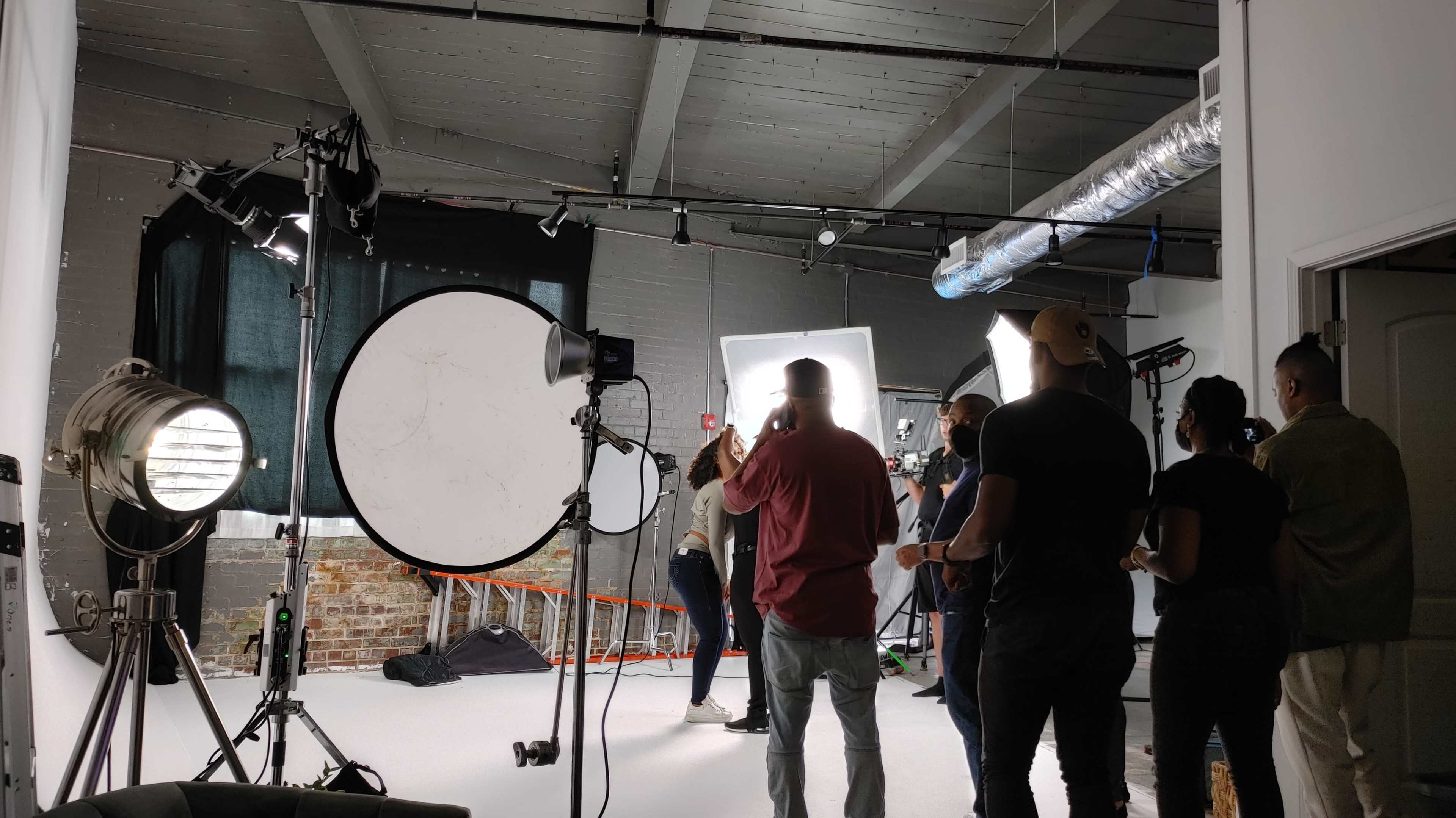 A photography studio is set up with multiple lights and a group of people preparing for a shoot.