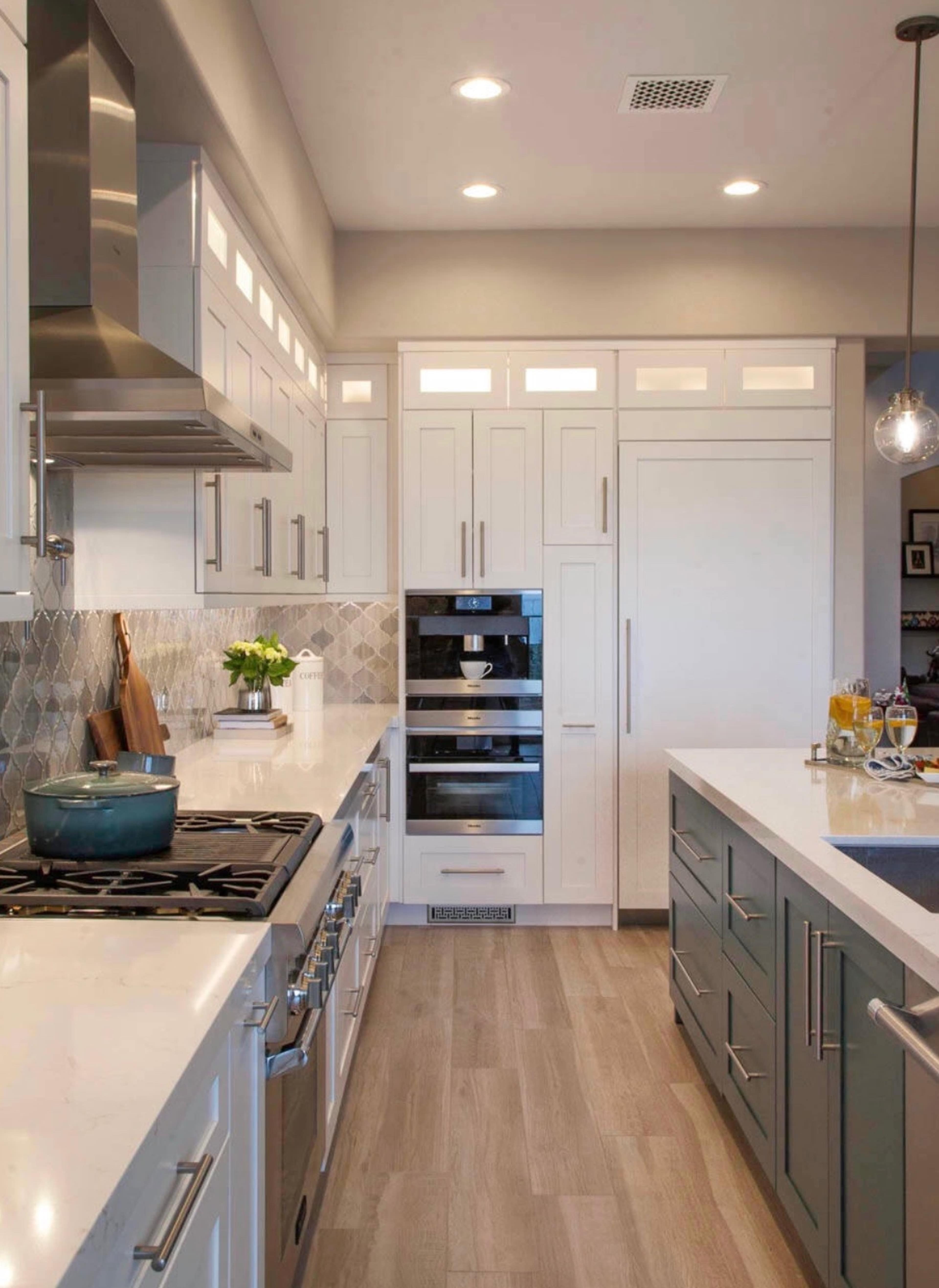 The image shows a modern kitchen with gray and white cabinetry, a stove, and a built-in wine cooler.