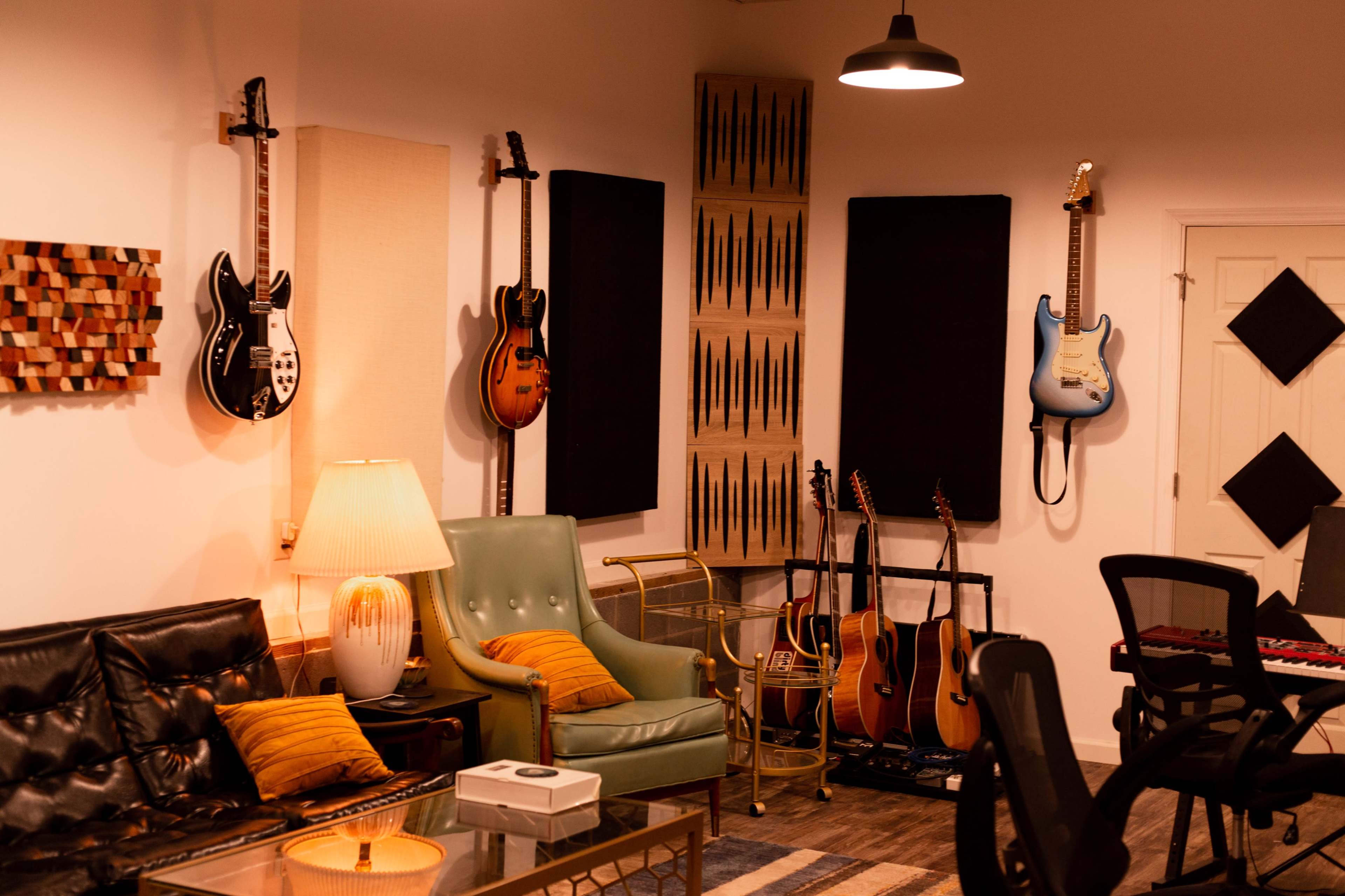 A music studio with various guitars displayed on the walls, seating areas, and a recording setup.