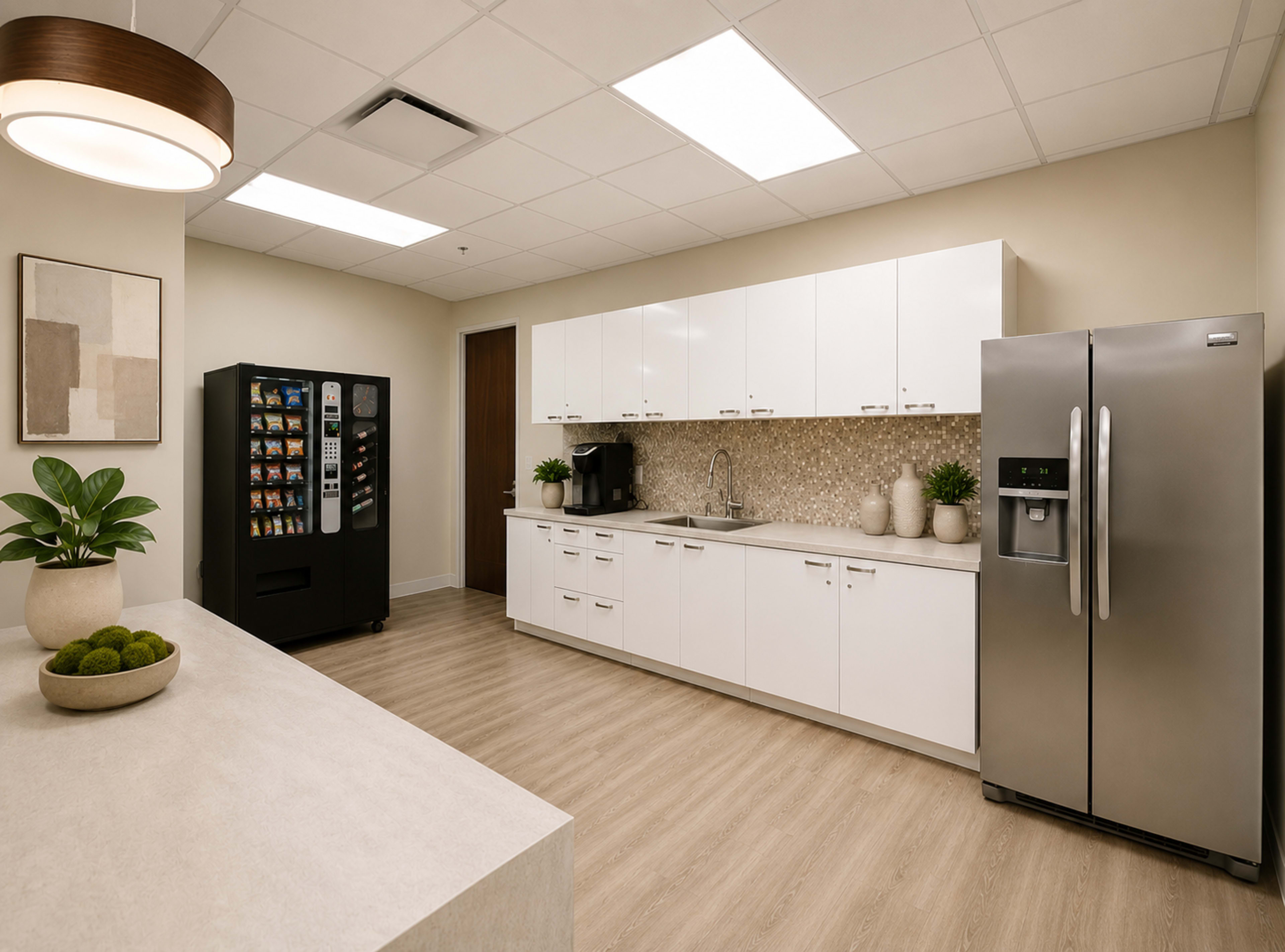 The image shows a modern kitchen area with white cabinetry, a stainless steel refrigerator, and a black vending machine, all set against a light-colored wall and floor.