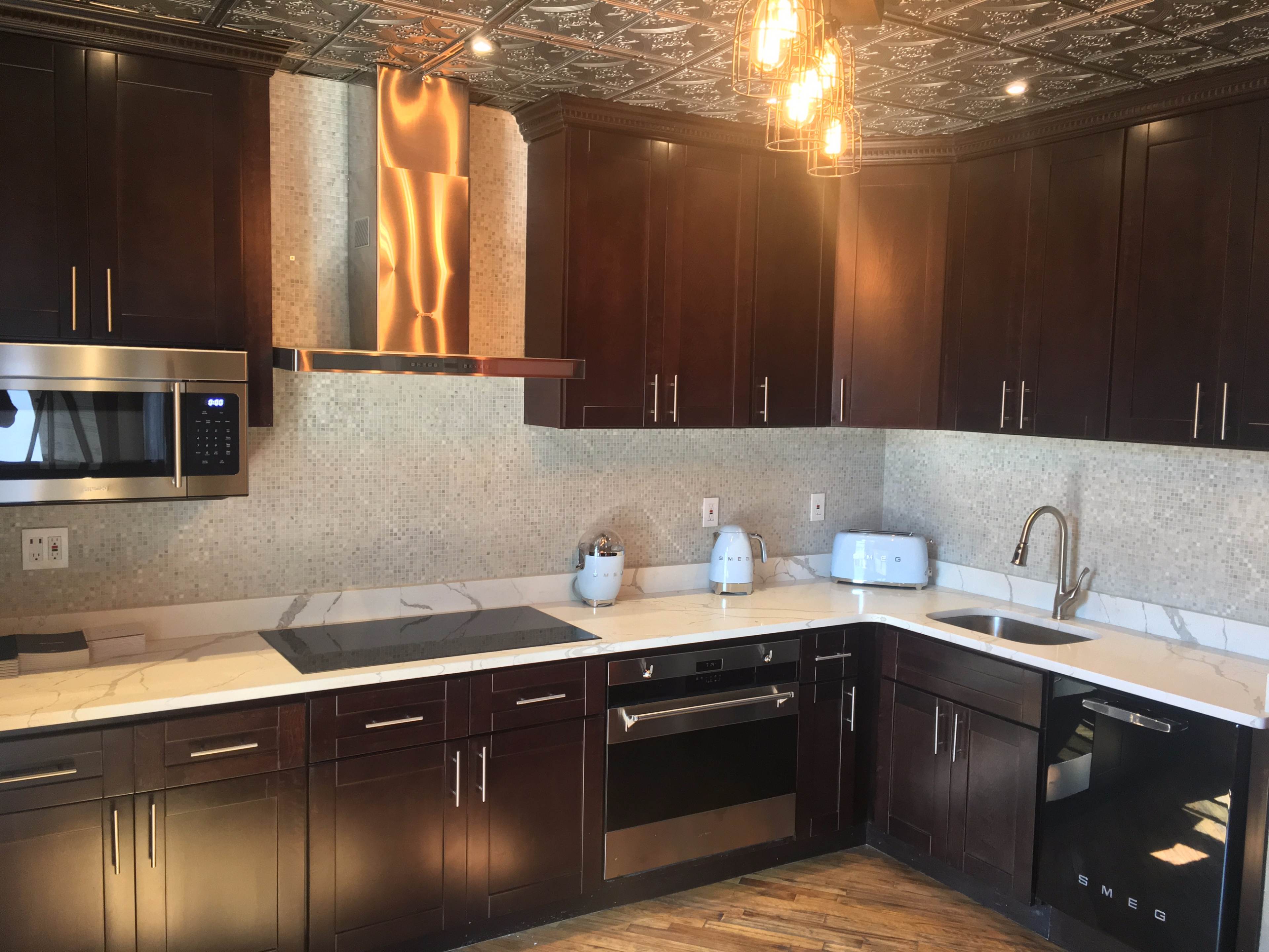 The kitchen features dark wooden cabinets, a marble countertop, stainless steel appliances, and a decorative ceiling.