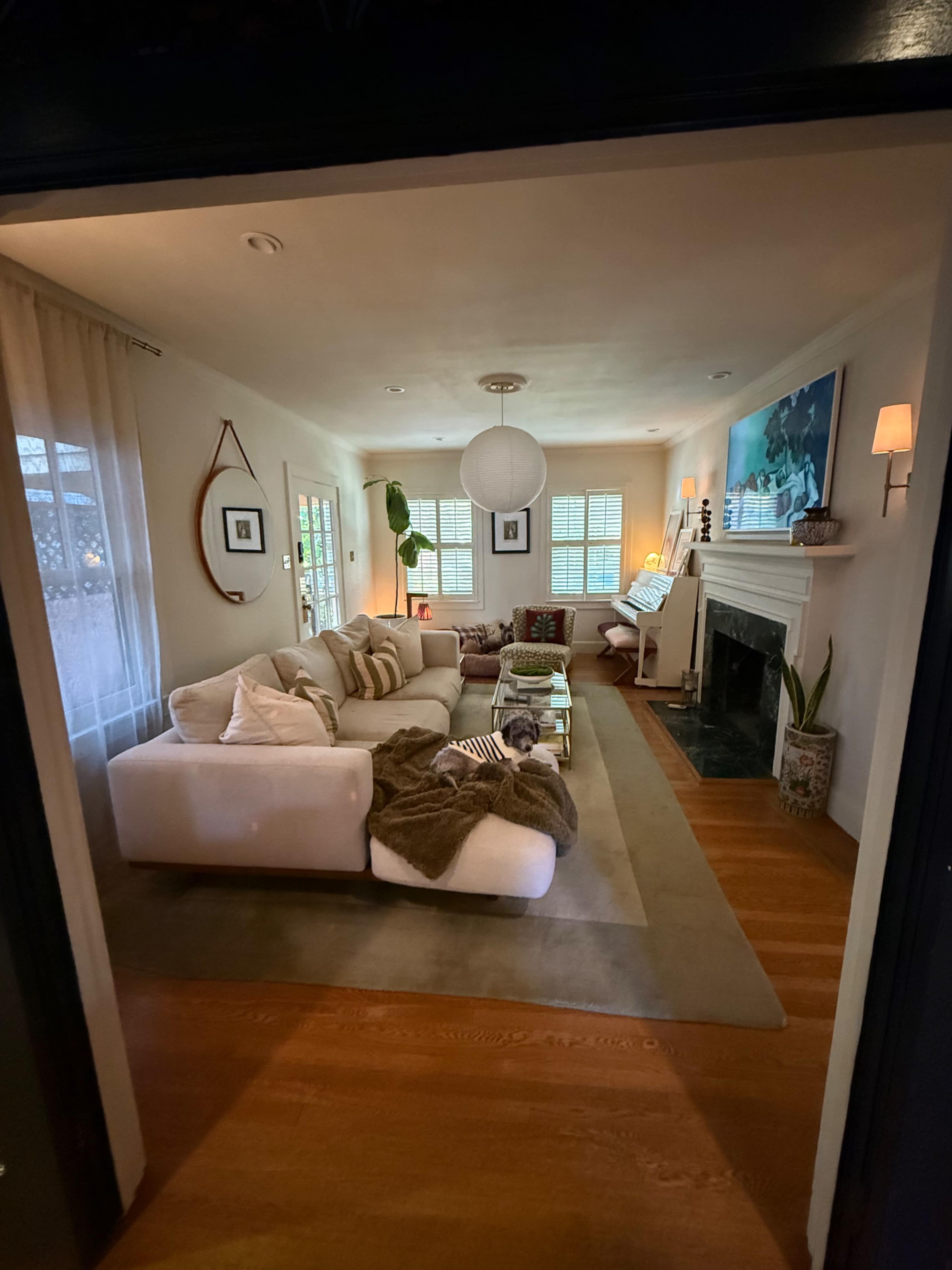 The image shows a cozy living room with a large white sectional sofa, a fireplace, and decorative artwork on the walls.
