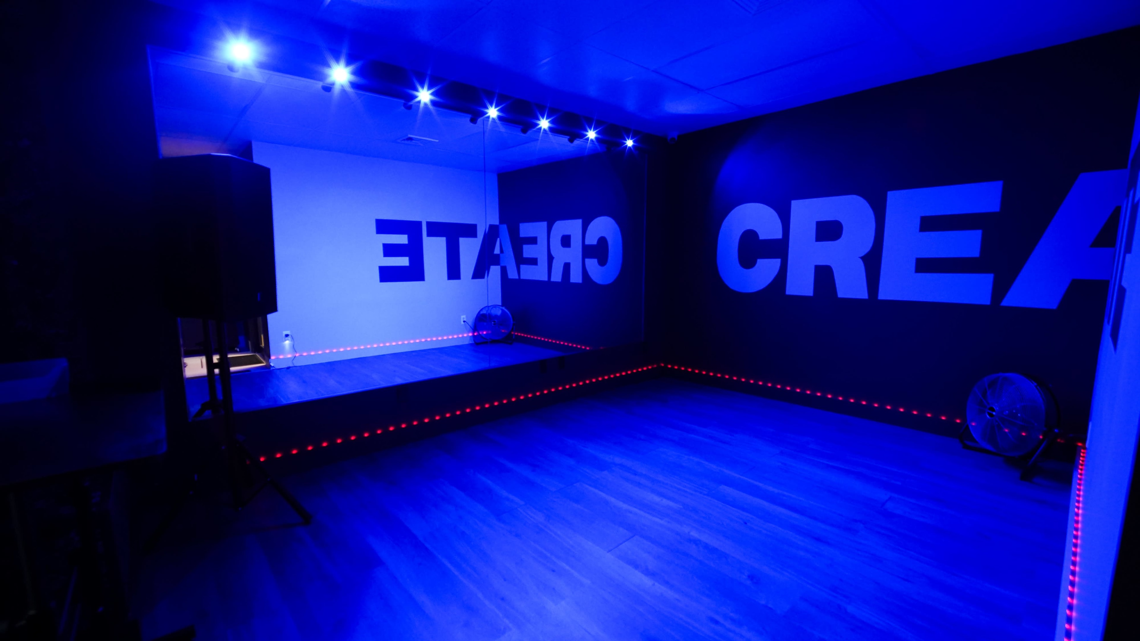 The image shows a modern room with blue lighting, featuring large wall text that spells out "CREATE" and a mirror on one side.