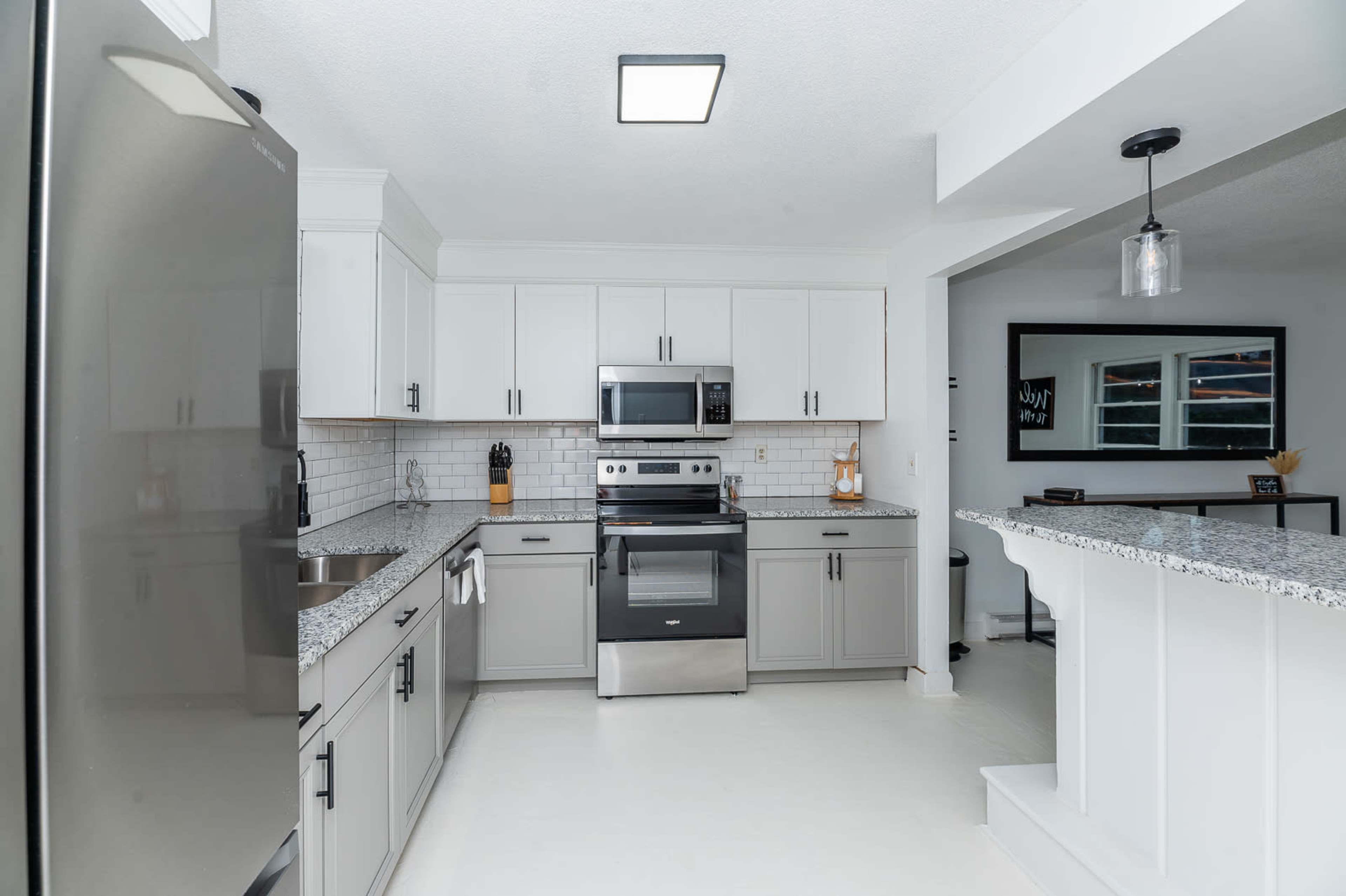 A modern kitchen with gray cabinetry, stainless steel appliances, and a granite countertop.