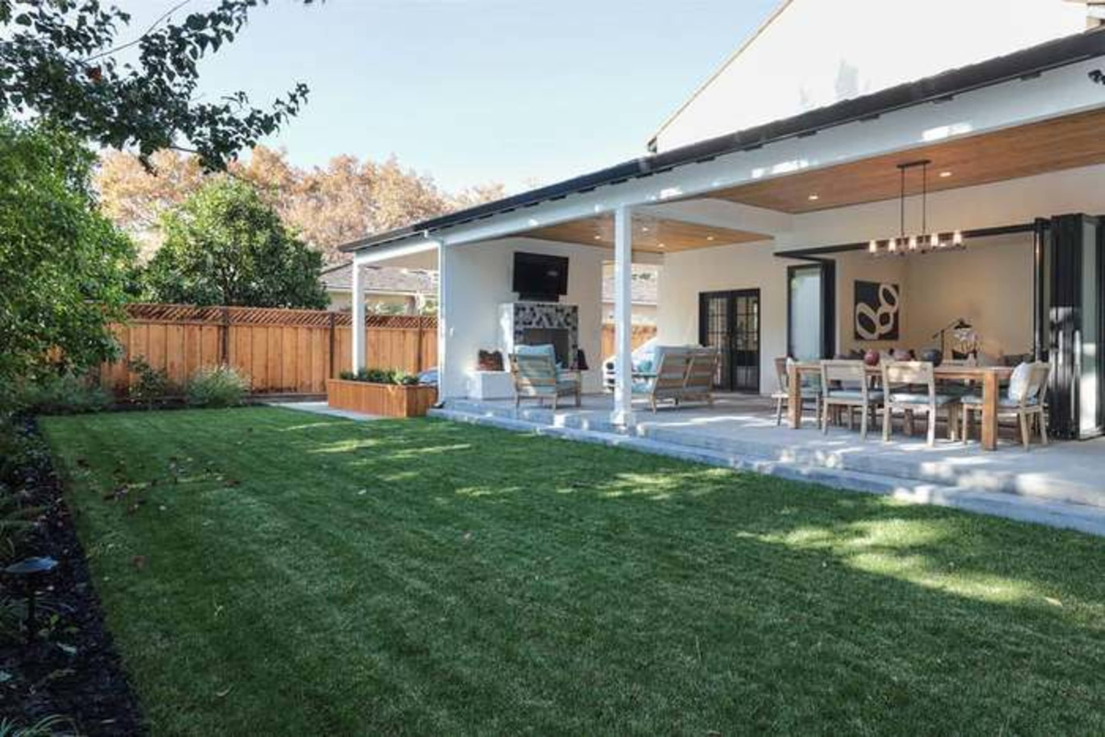 A well-manicured backyard features a patio with outdoor seating and a dining area adjacent to a lawn.