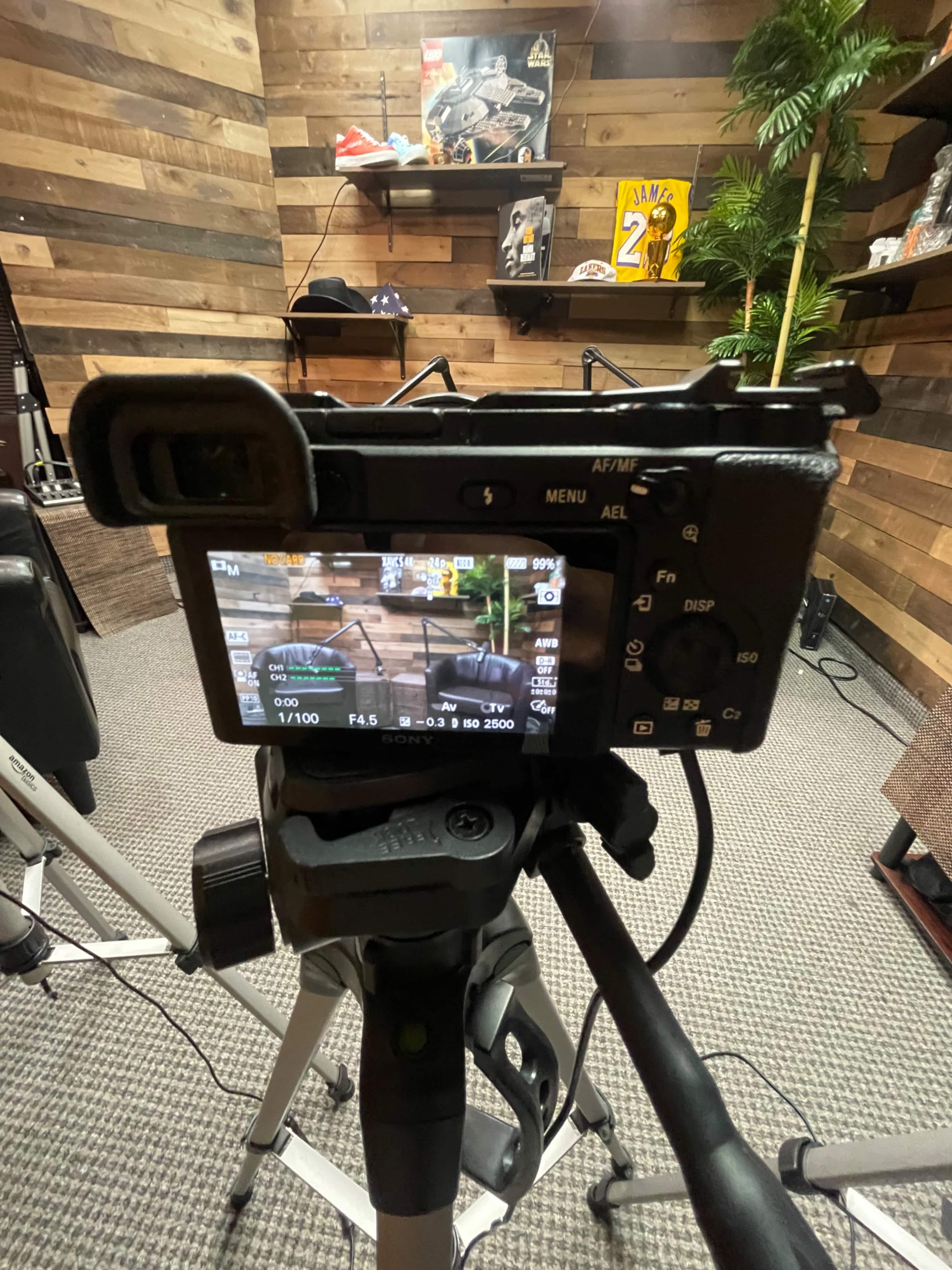 A camera is positioned on a tripod, displaying an image of a room with wooden walls and various sports memorabilia in the background.
