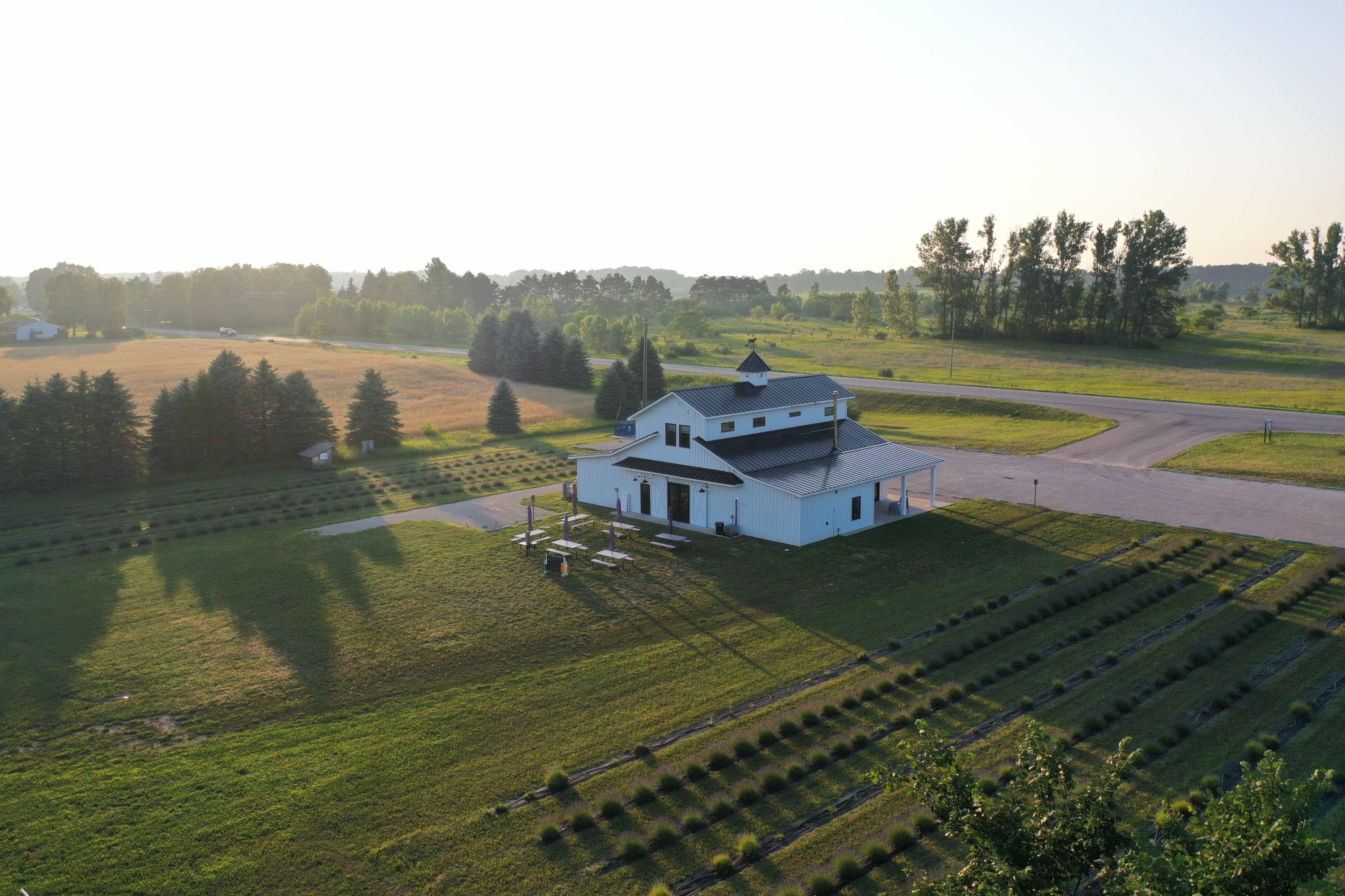 A modern white building sits surrounded by neatly arranged landscaping in a rural area under a clear sky.