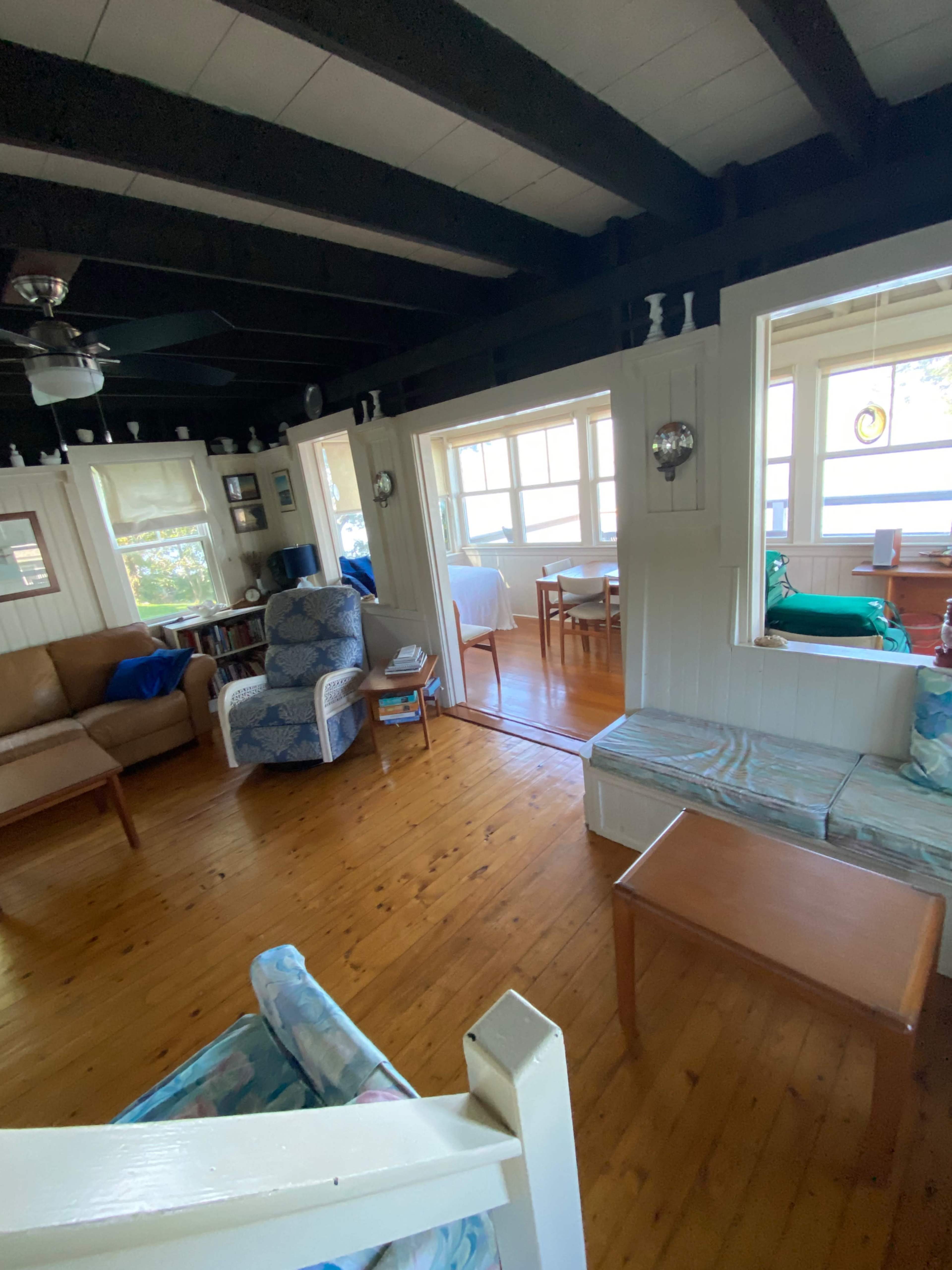 A living area features two couches, a wooden table, and multiple windows allowing natural light.