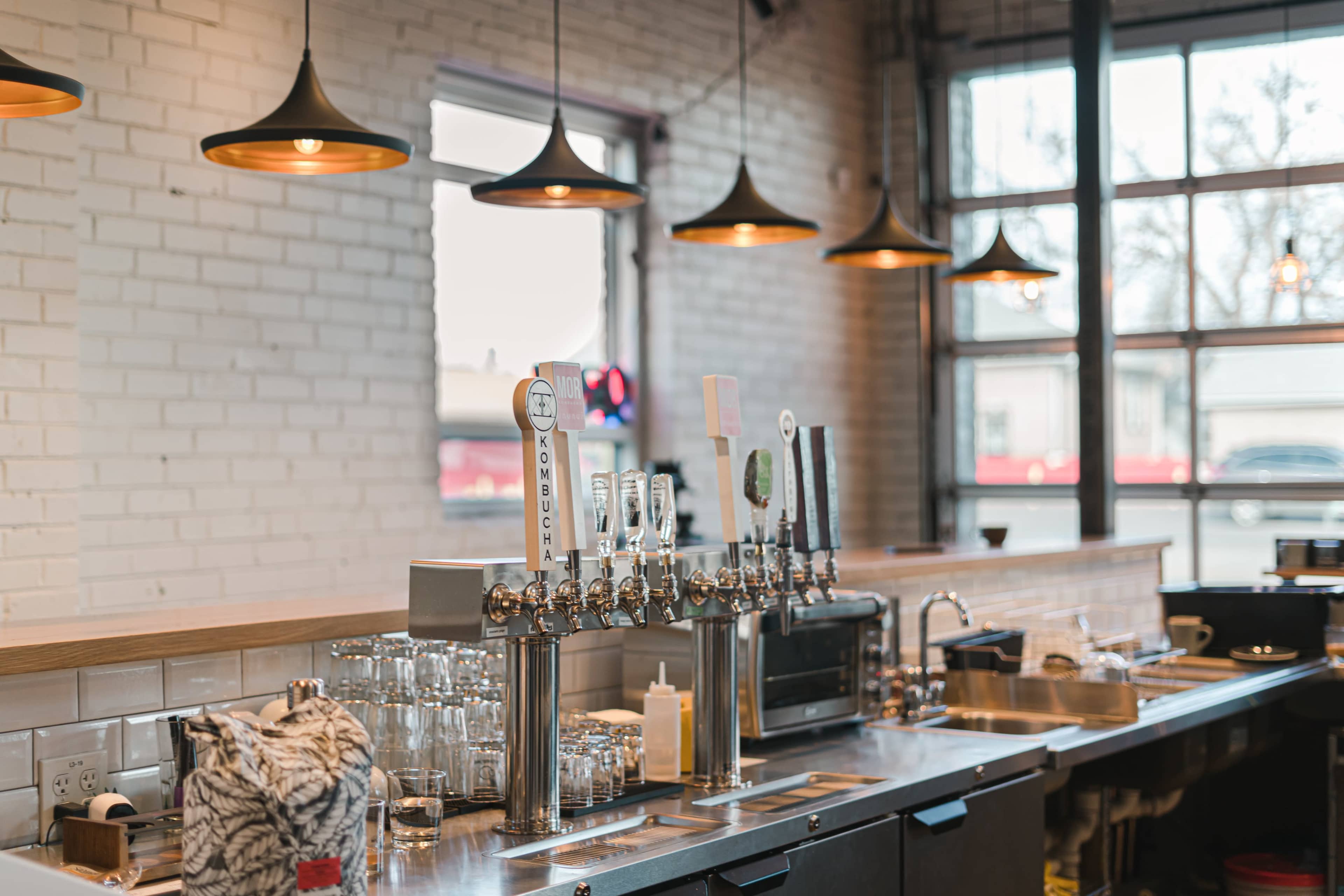 A bar with multiple beer taps, glassware, and lighting fixtures in a modern setting.