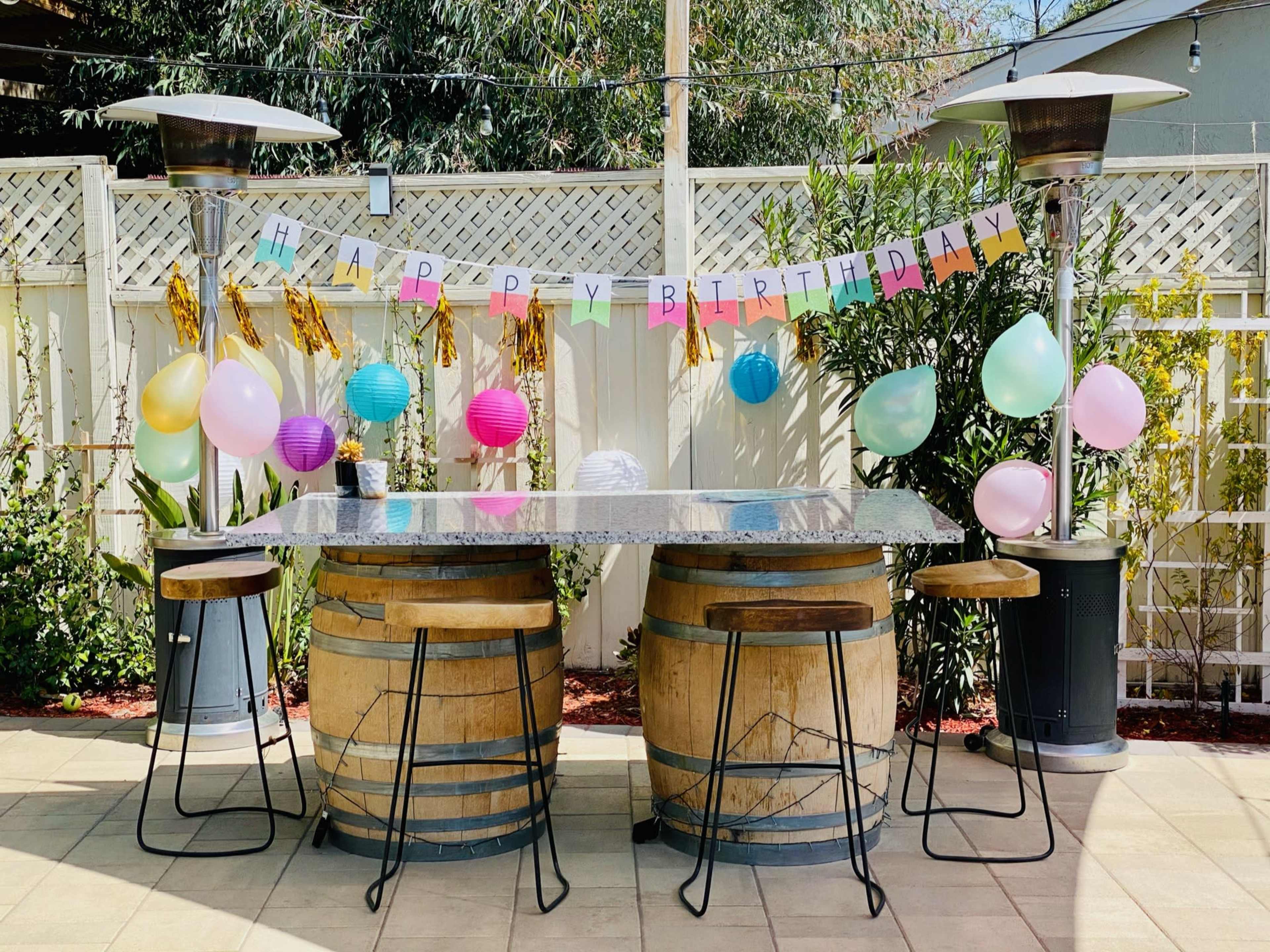 A festive outdoor bar setup with a "Happy Birthday" banner, colorful balloons, and decorative lanterns.