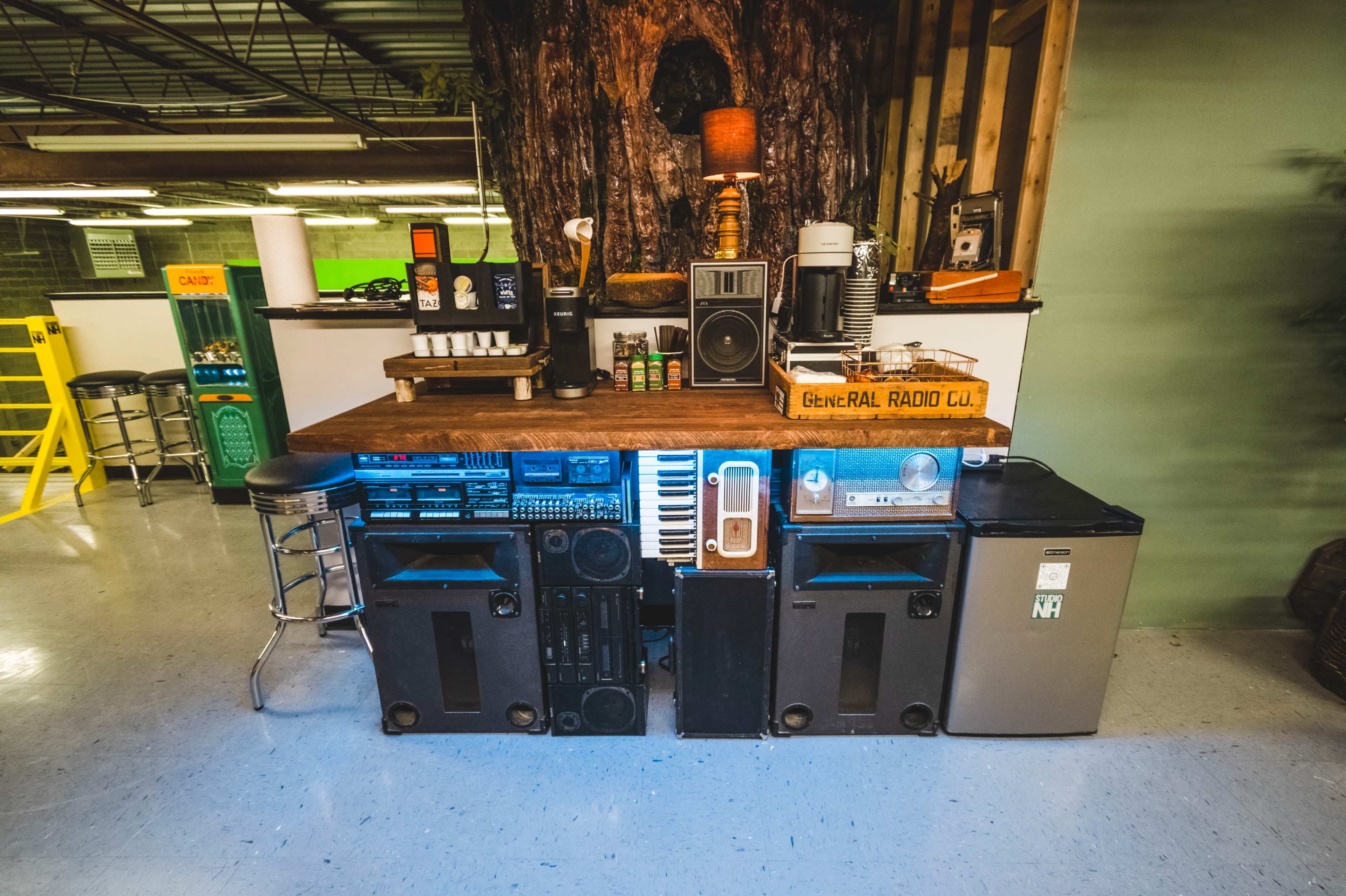 A cluttered counter arrangement made from various audio equipment, appliances, and a wooden tabletop.