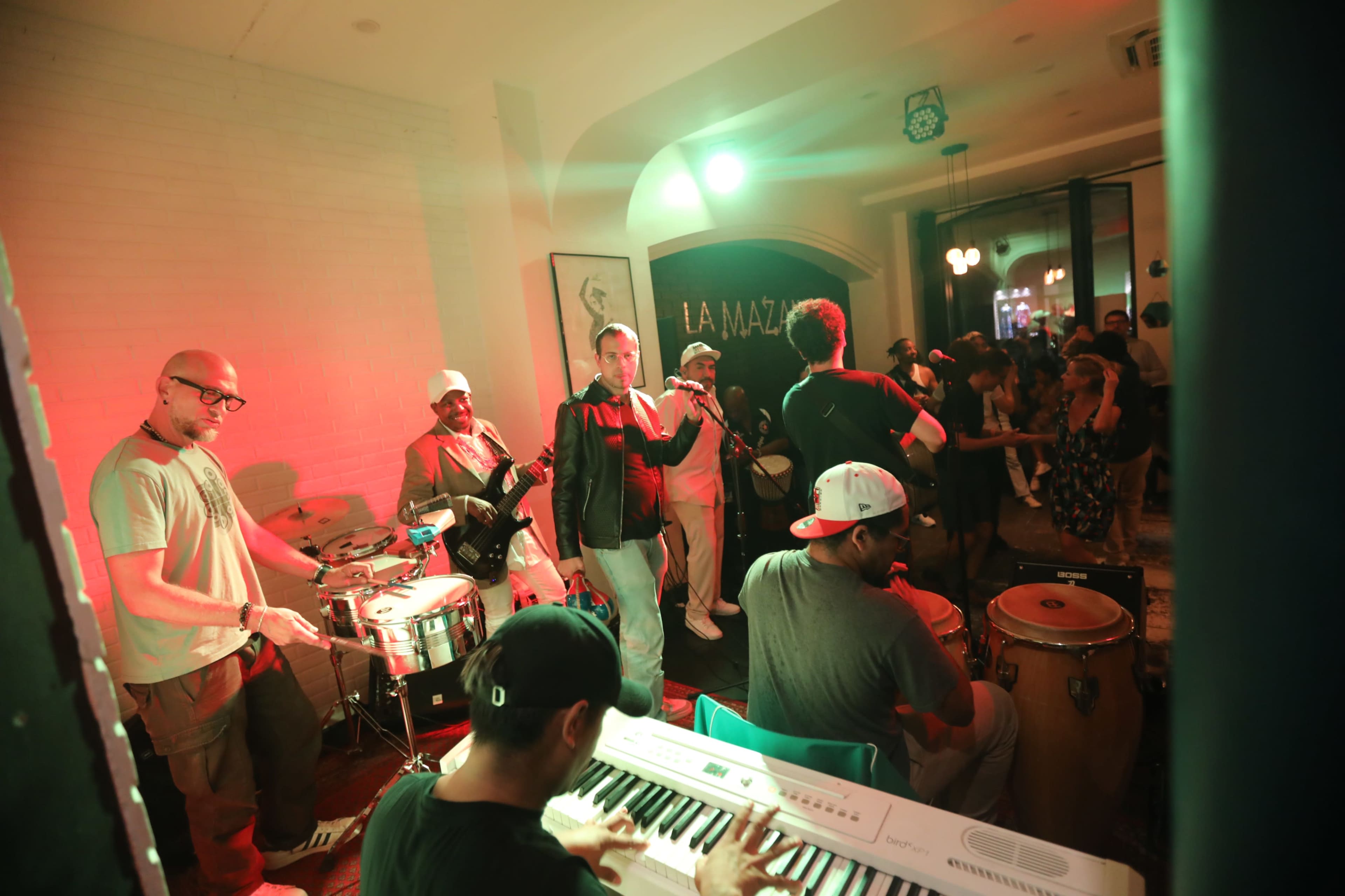 A live band performs on a stage in a lively, dimly lit venue filled with people.