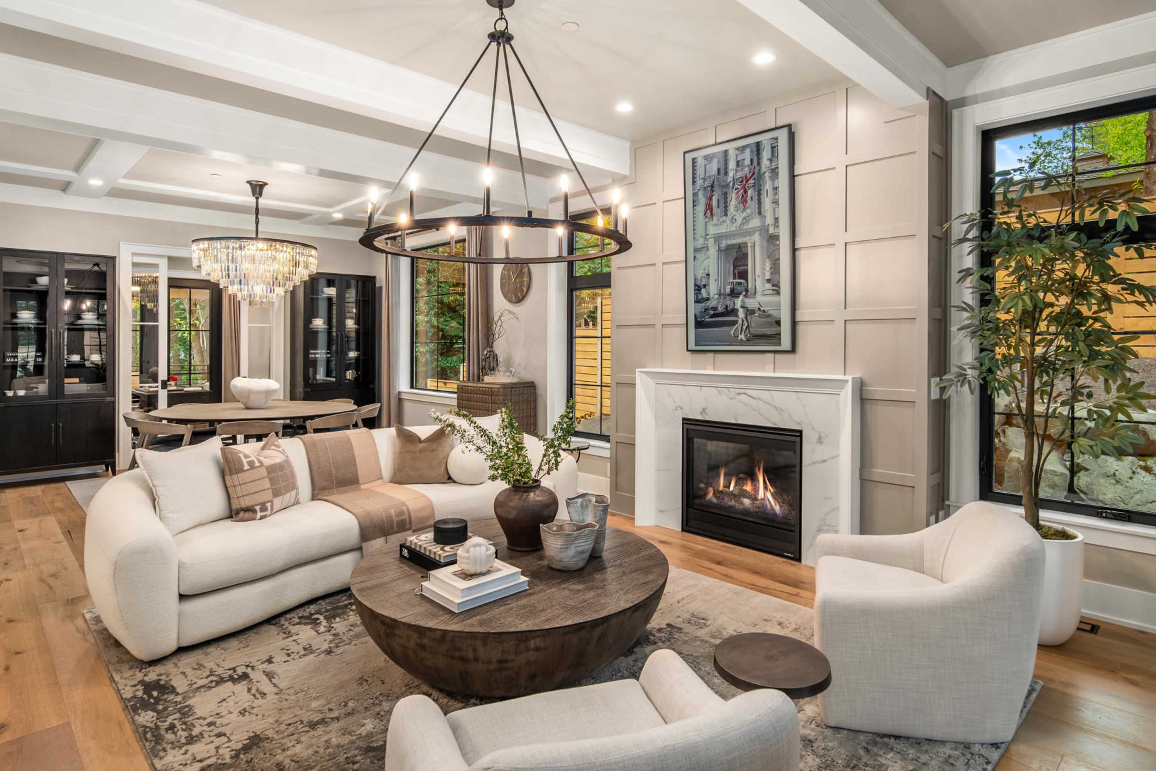 The image showcases a modern living room with a cozy circular coffee table, a fireplace, and elegant furniture arranged around a soft area rug.