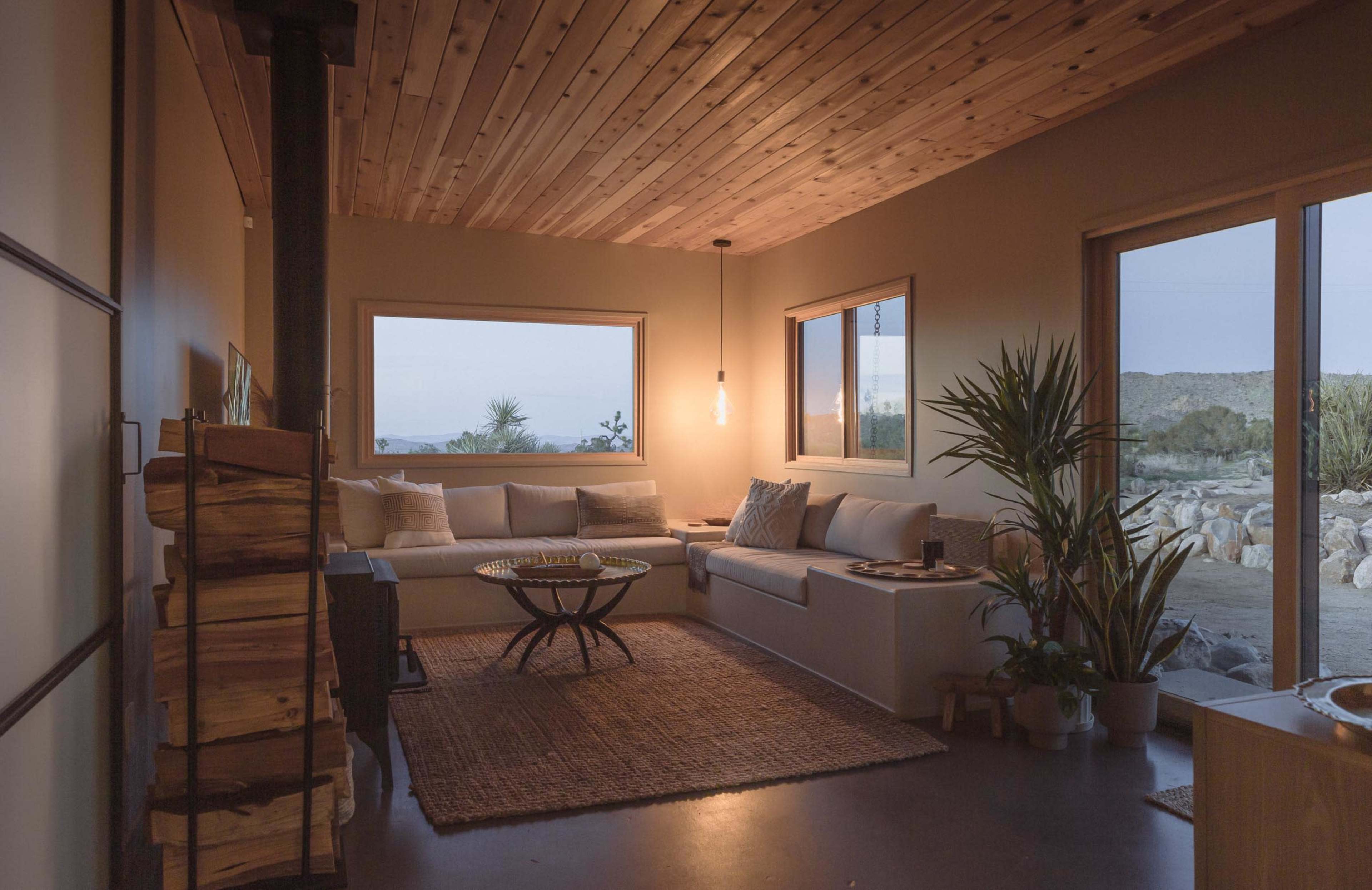 A spacious living room features a sleek sofa, a coffee table, and large windows offering views of a desert landscape.