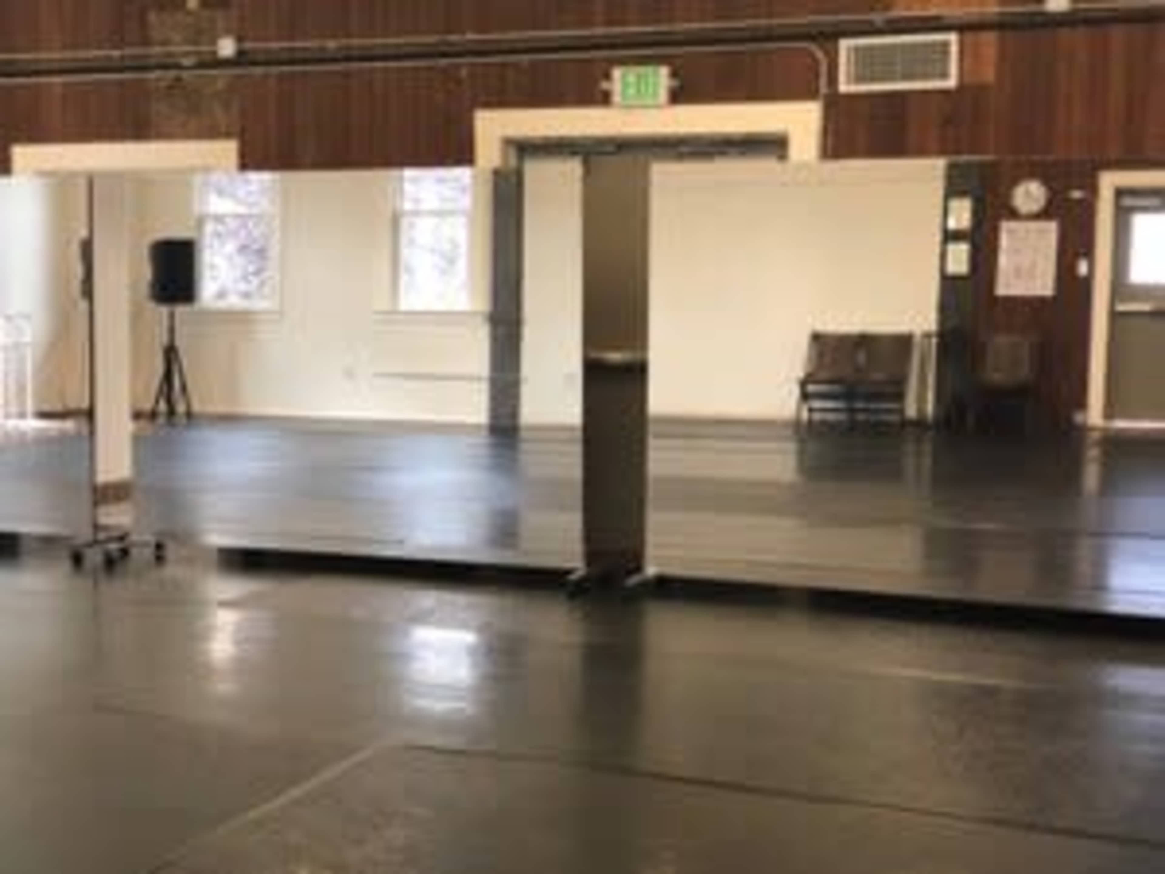 The image shows a spacious dance studio with large mirrors along one wall and a smooth, dark floor.