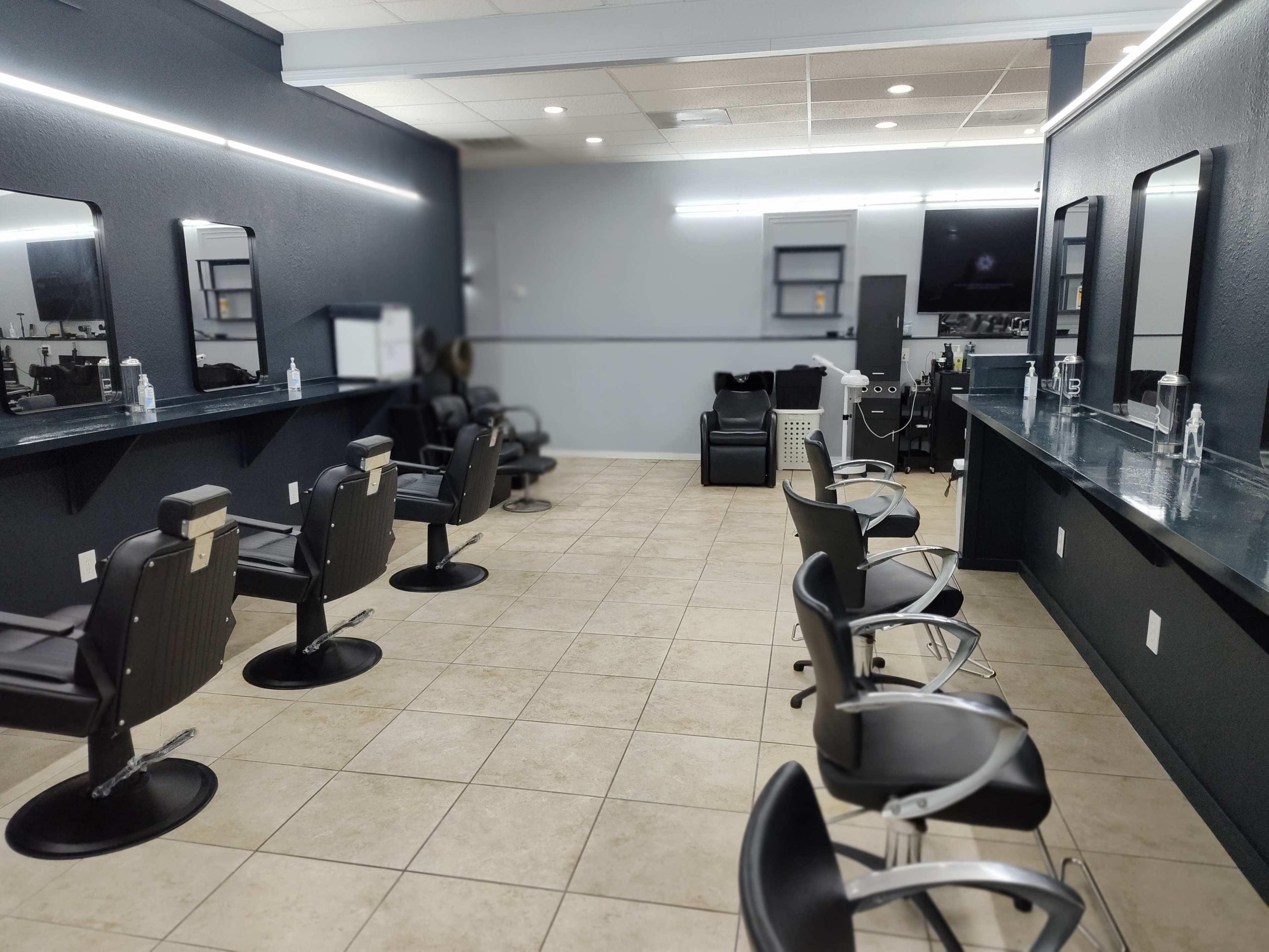 The interior of a hair salon with several styling chairs, mirrors, and a reception area.