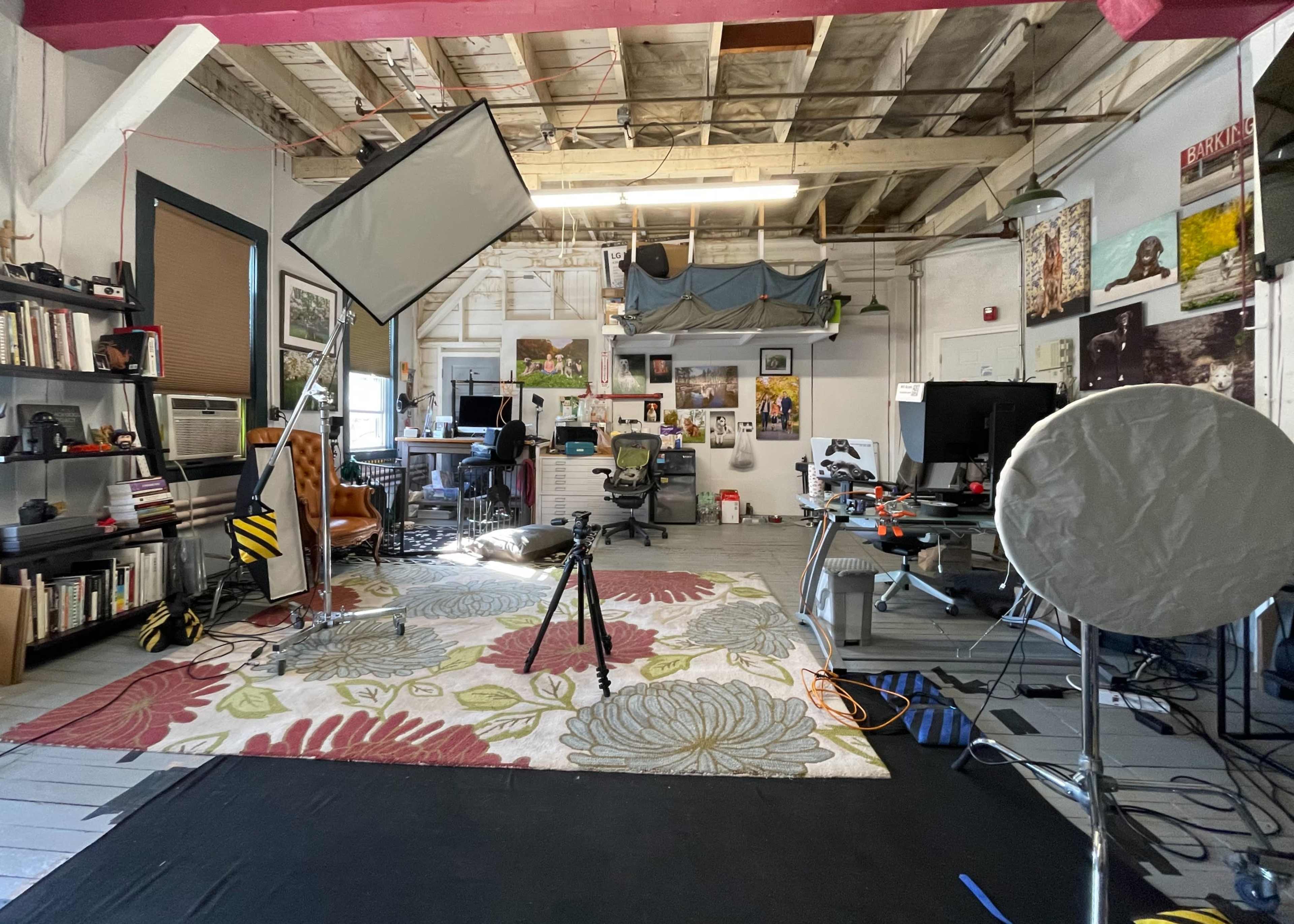 A spacious studio with various photography equipment, a large area rug, and workstations set up for creative projects.