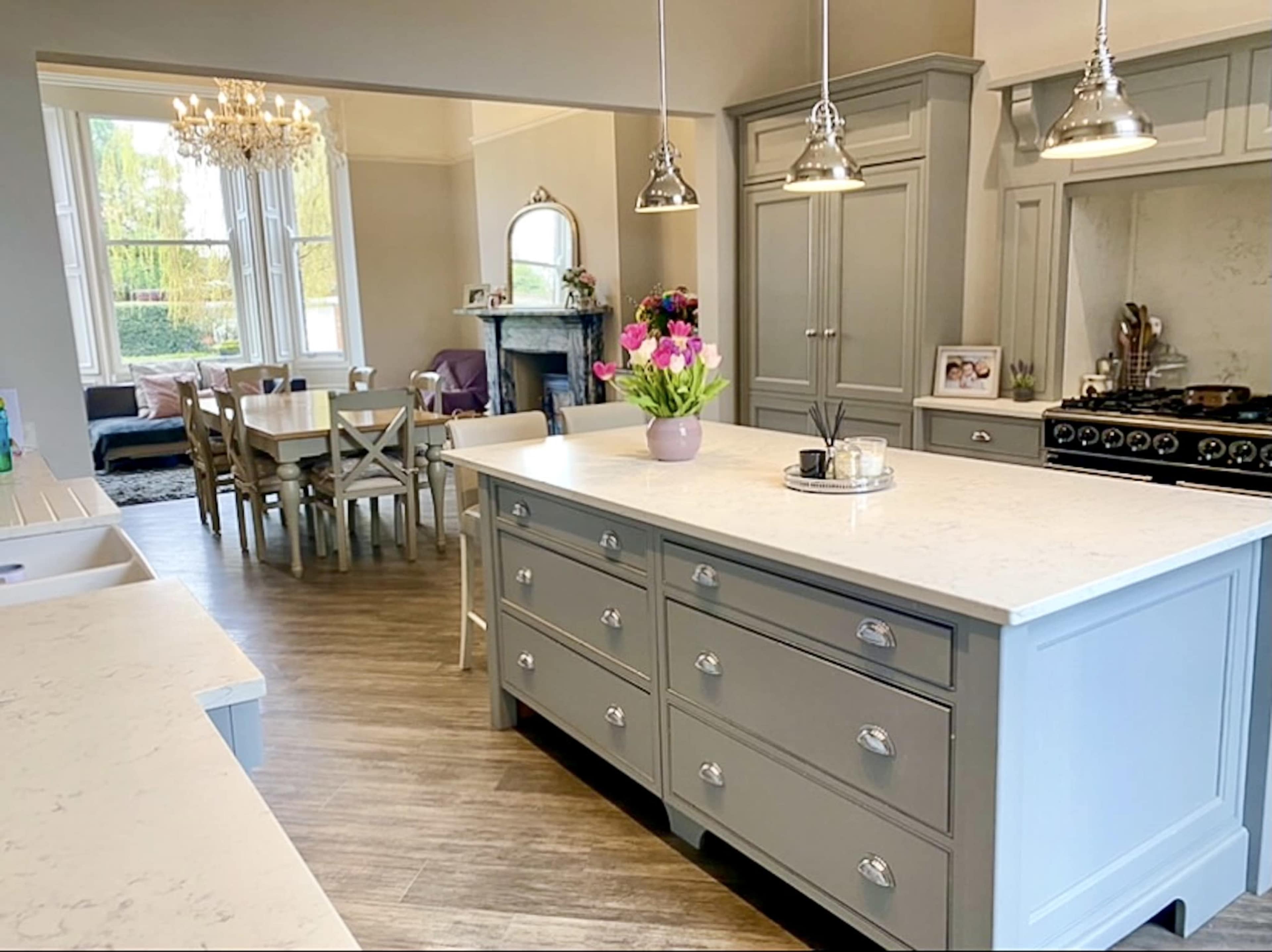A spacious kitchen with a gray kitchen island, pendant lighting, and an adjoining dining area visible in the background.