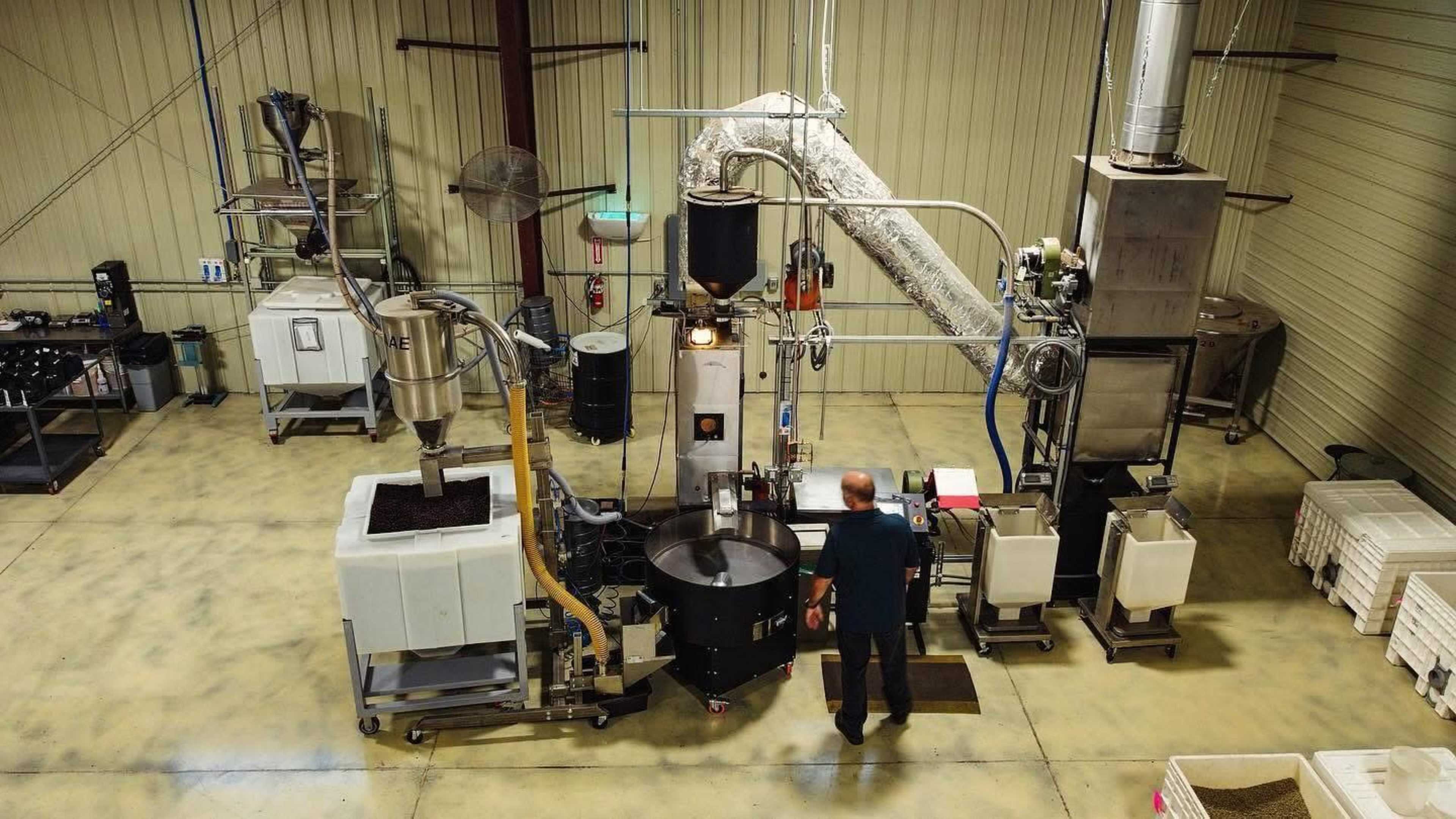 A person is operating a manufacturing machine in a clean and organized industrial facility.