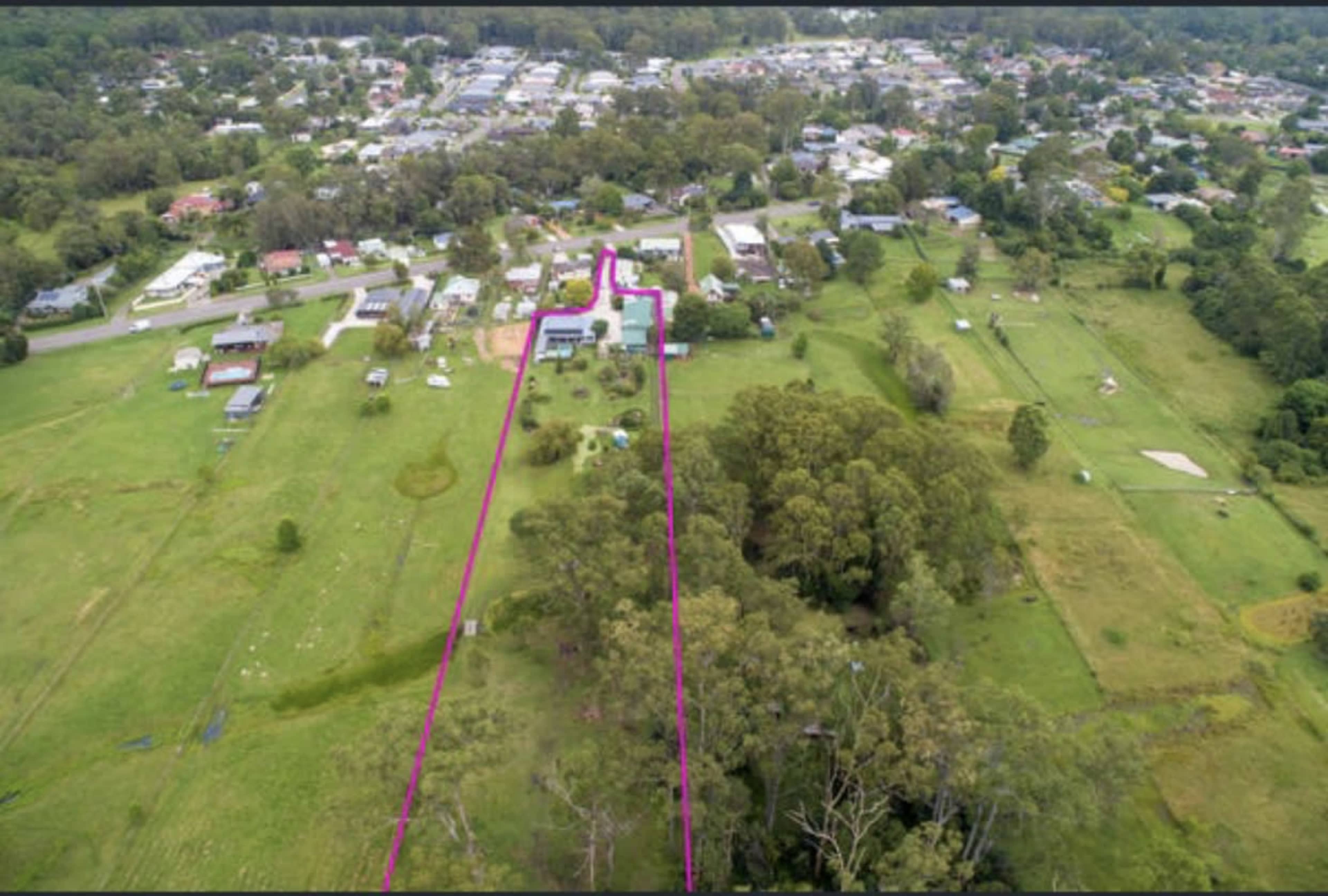 The aerial view shows a residential area with houses, roads, and greenery, marked by a pink outline guiding through a pathway.