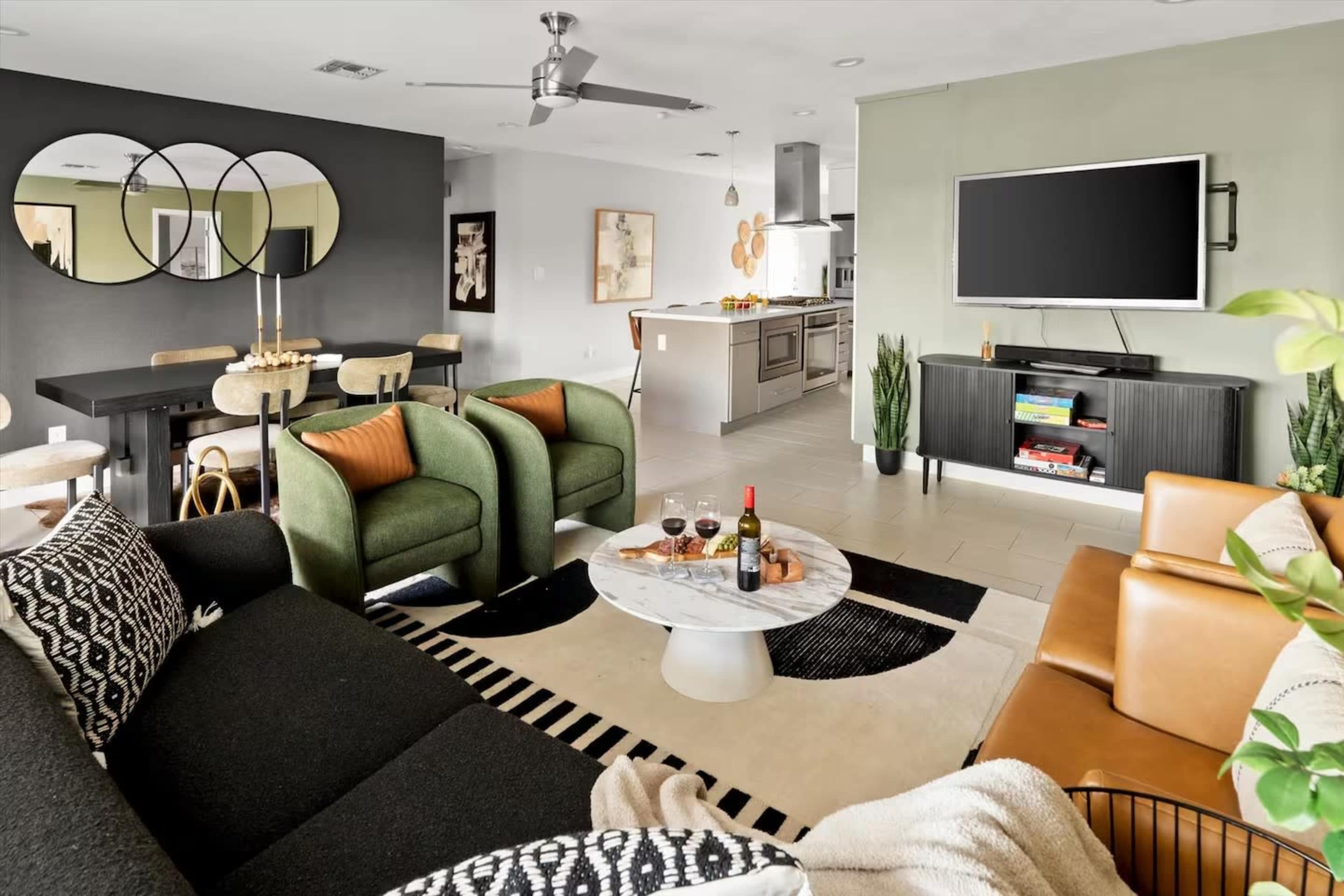 A modern living room features a mix of seating arrangements, a marble coffee table with snacks and drinks, and a contemporary entertainment setup.