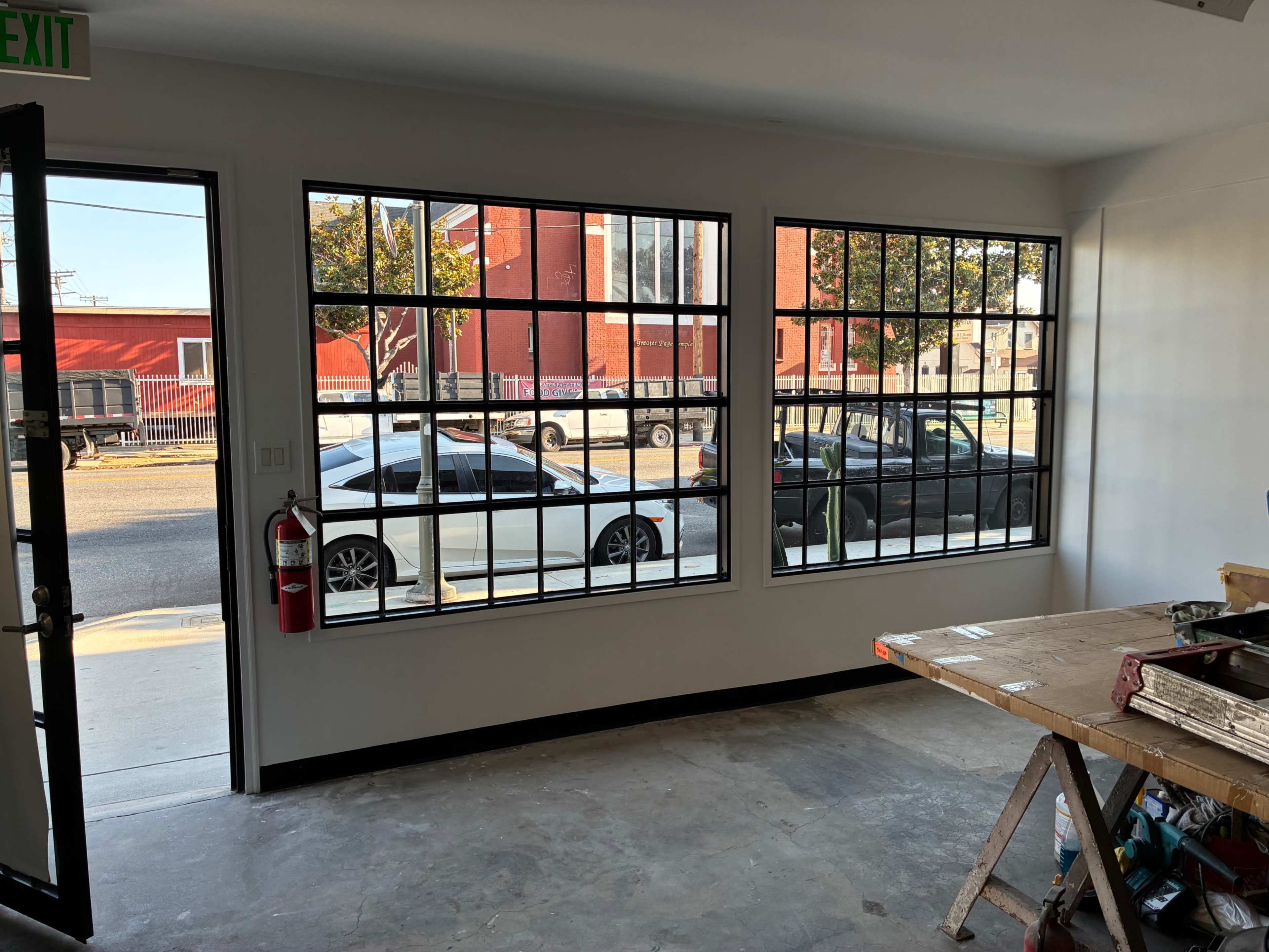 Empty modern storefront commercial space with concrete floors, large custom steel windows and oversized door. Image in South Los Angeles, Los Angeles, CA