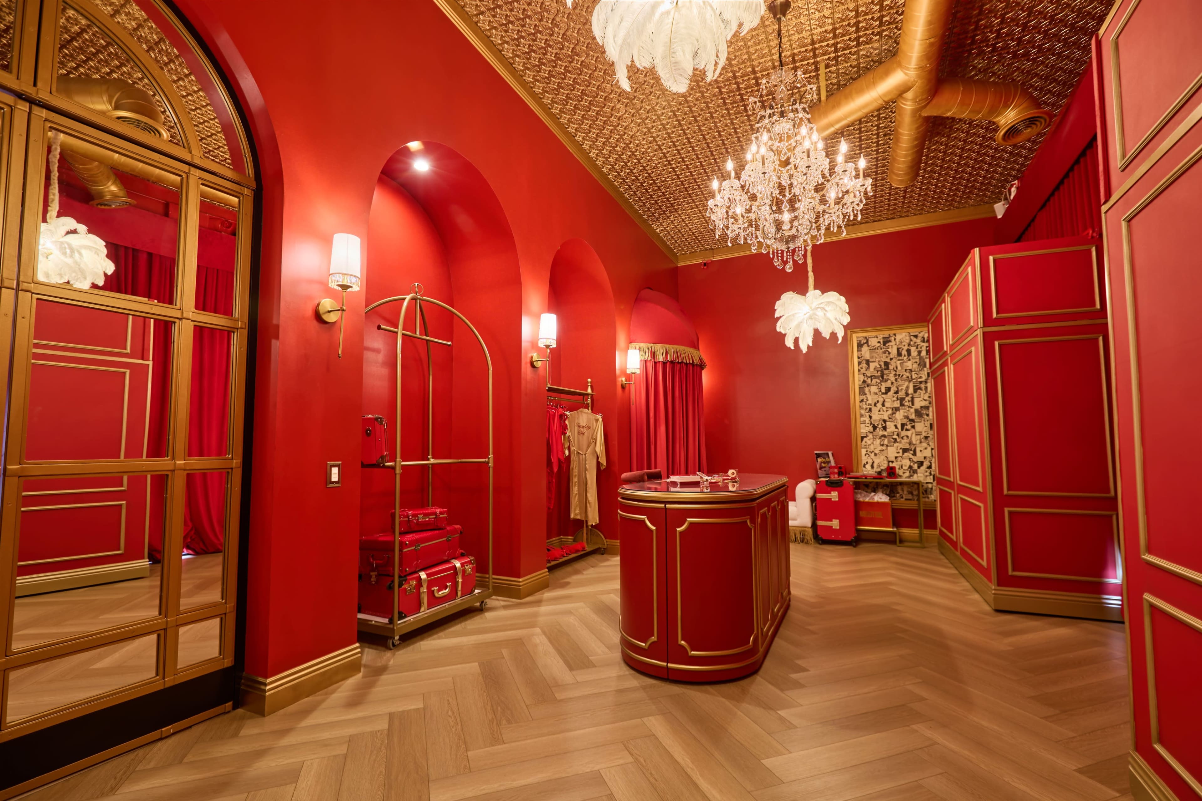The image shows a vibrant red room with an intricate ceiling, featuring a central reception counter and elegant light fixtures.