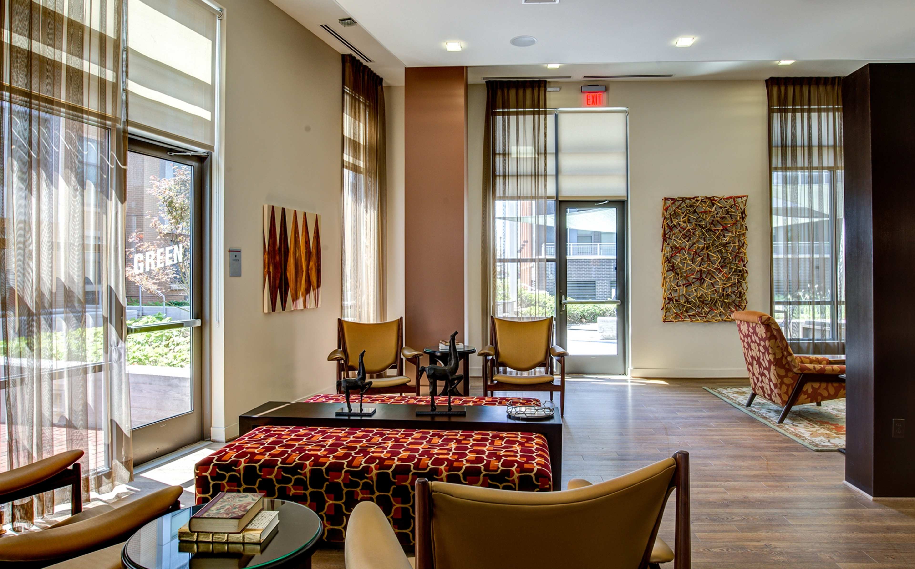A modern lounge area with large windows, comfortable seating, and a coffee table, complemented by colorful artwork on the walls.