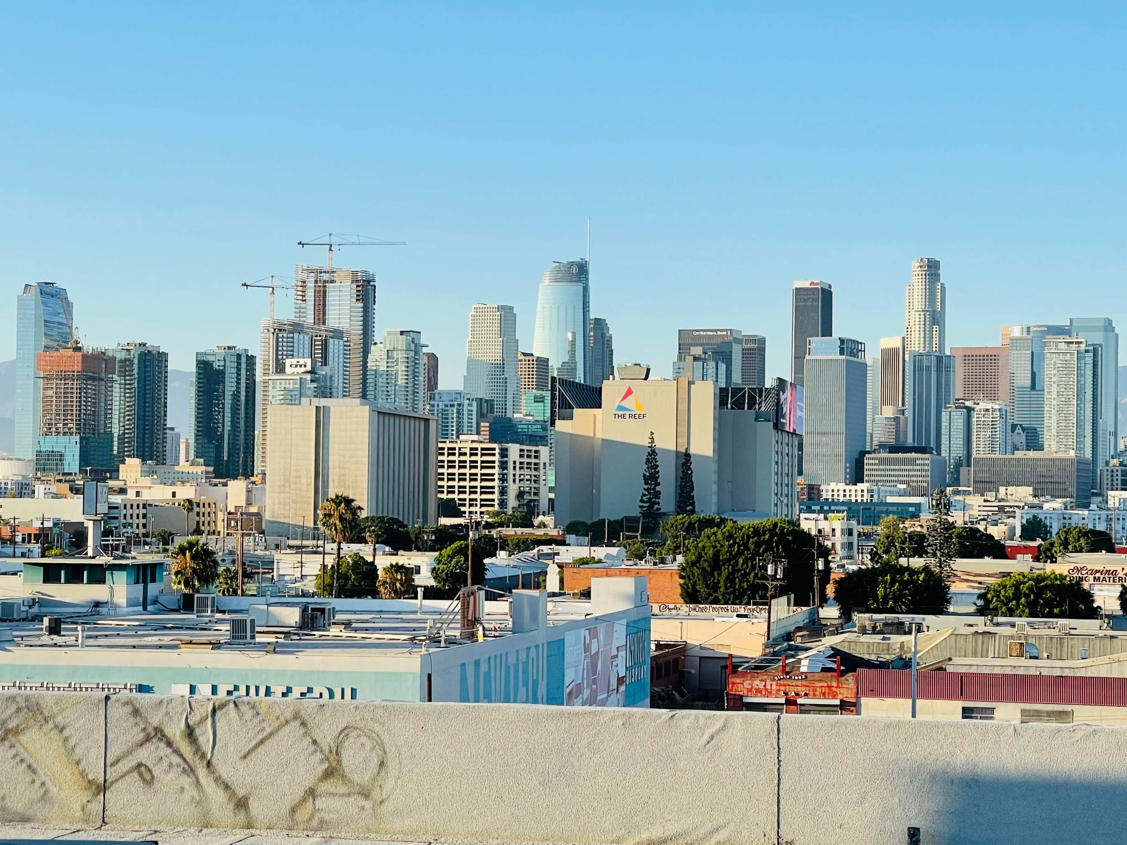A view of the downtown Los Angeles skyline with various high-rise buildings and a clear blue sky.