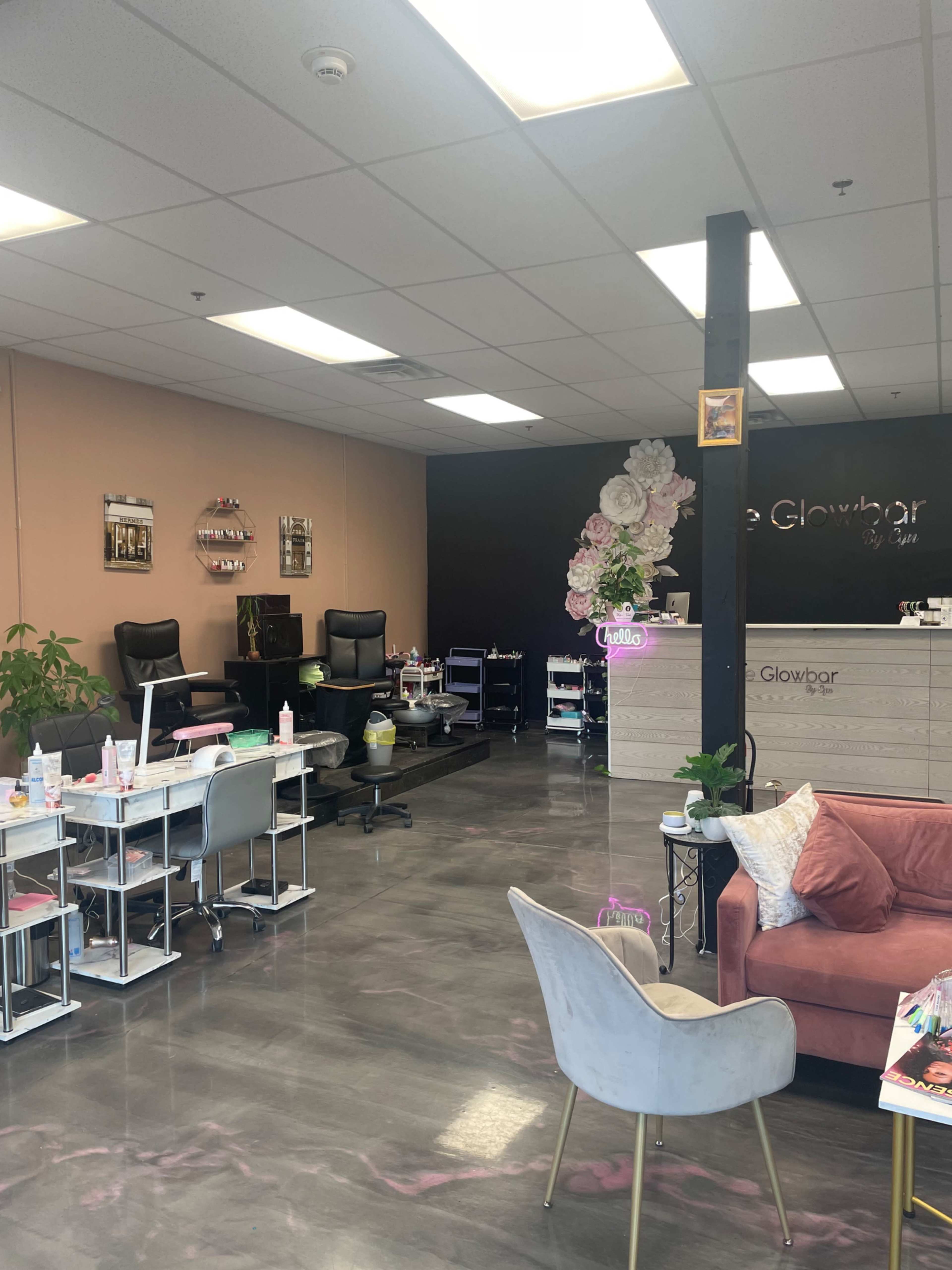 A beauty salon interior featuring several treatment chairs, tables, and a reception desk adorned with decorative flowers.