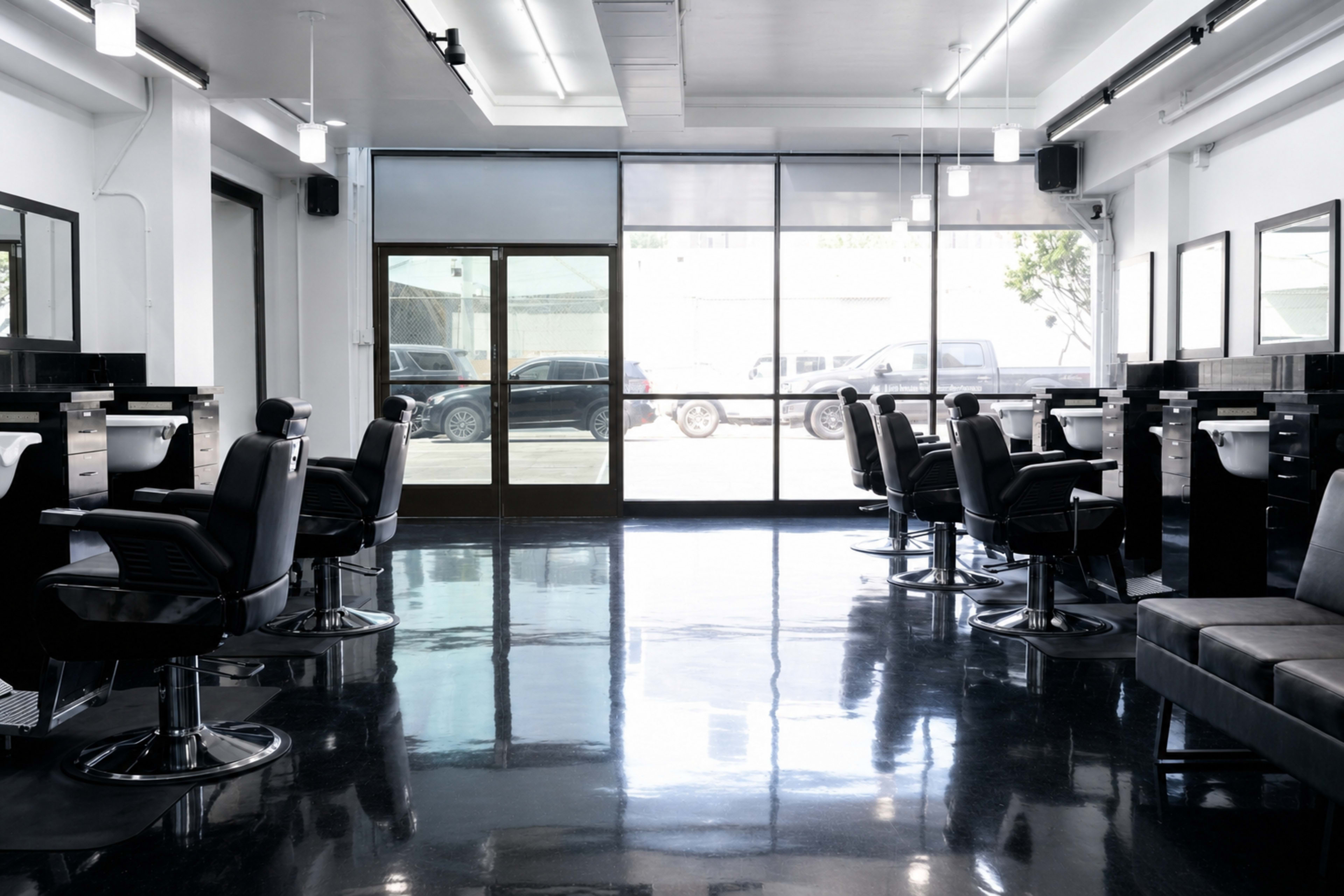The image shows a modern hair salon with sleek black styling chairs and large mirrors against a polished black floor.