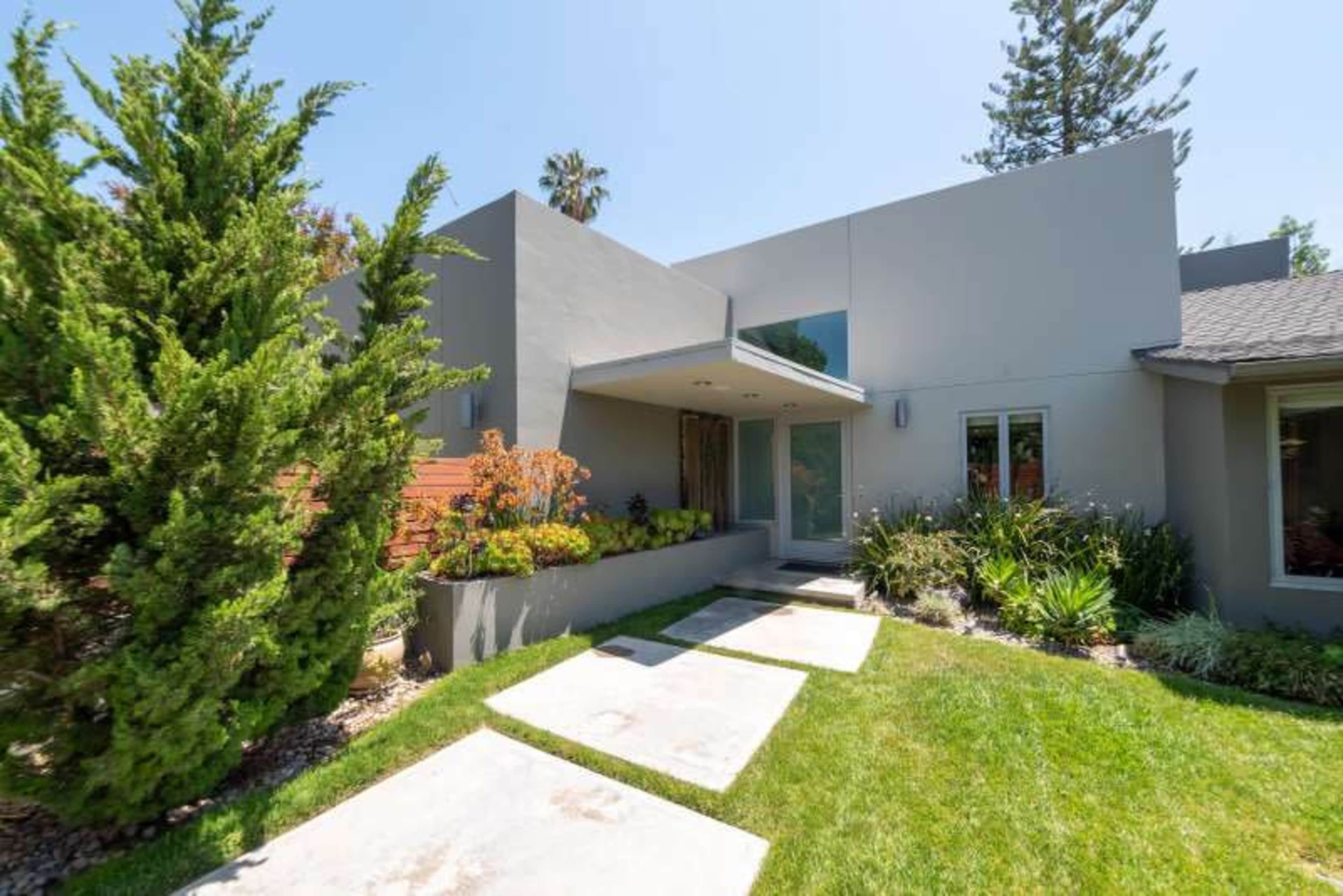 A modern gray house with a landscaped front yard, featuring a pathway leading to the entrance.
