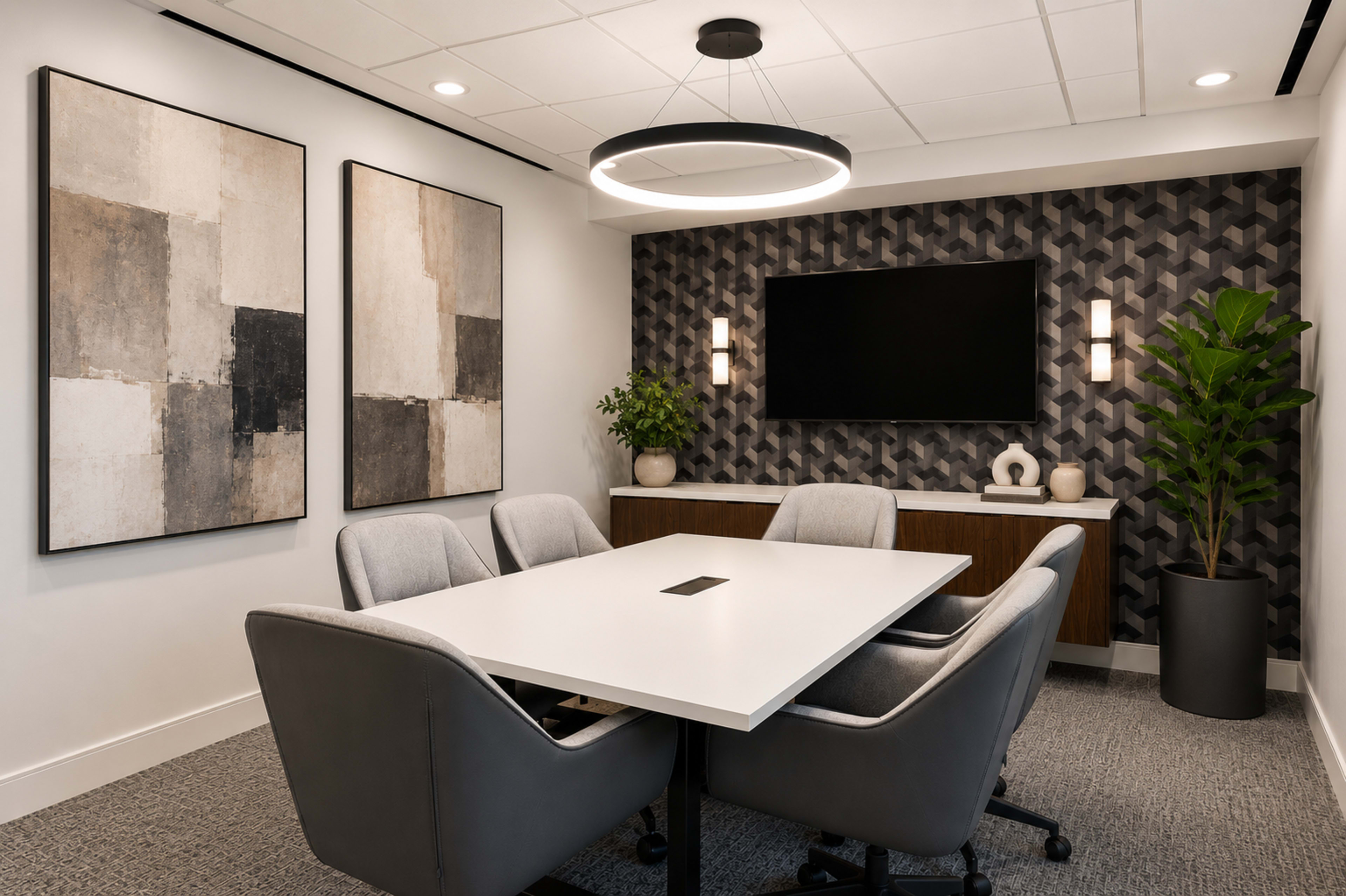 The image shows a modern conference room featuring a white table surrounded by gray chairs, two abstract artworks on the walls, and a television mounted on the dark geometric-patterned wallpaper.