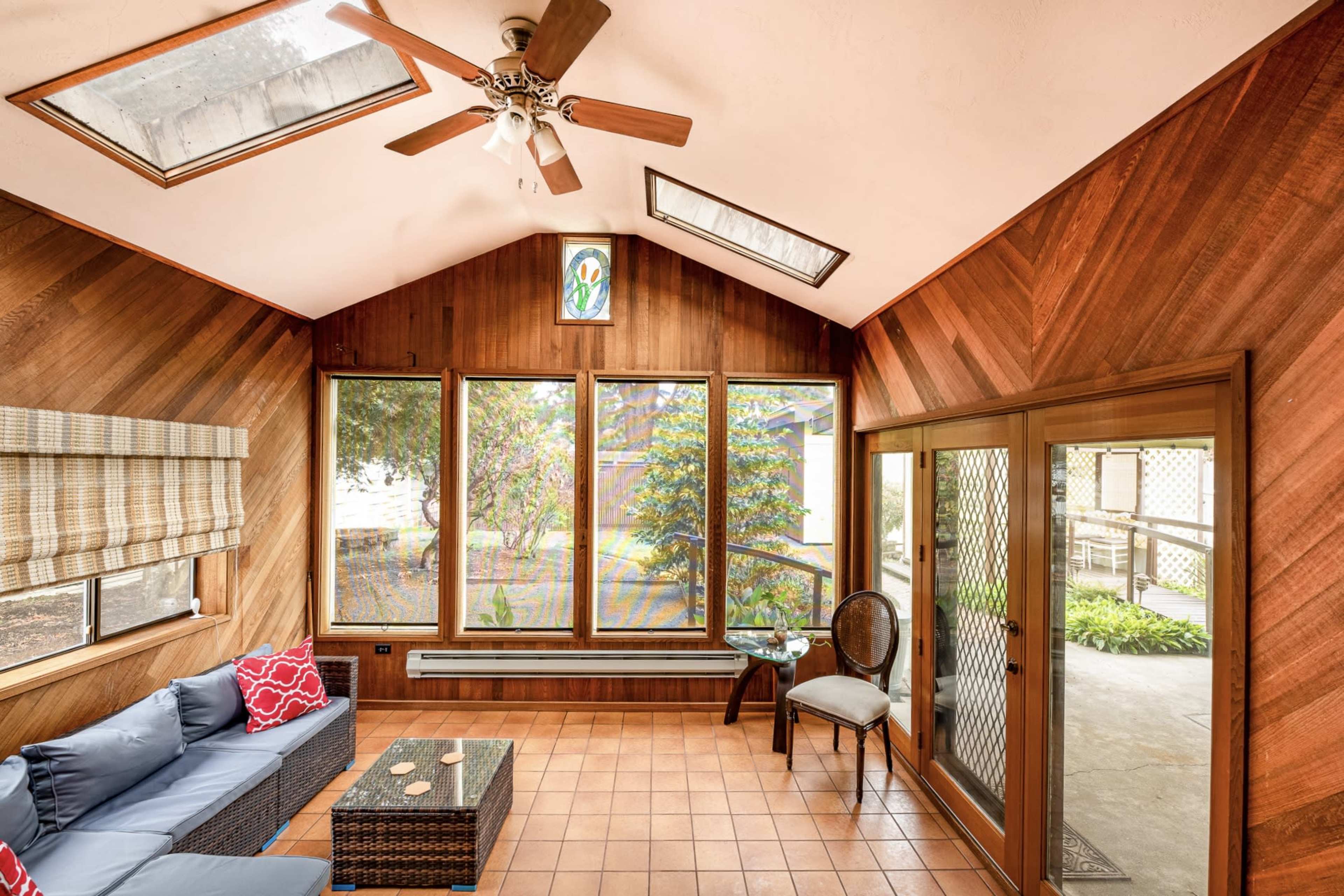 The room features wooden paneling, large windows for natural light, and a seating area with a couch and coffee table.