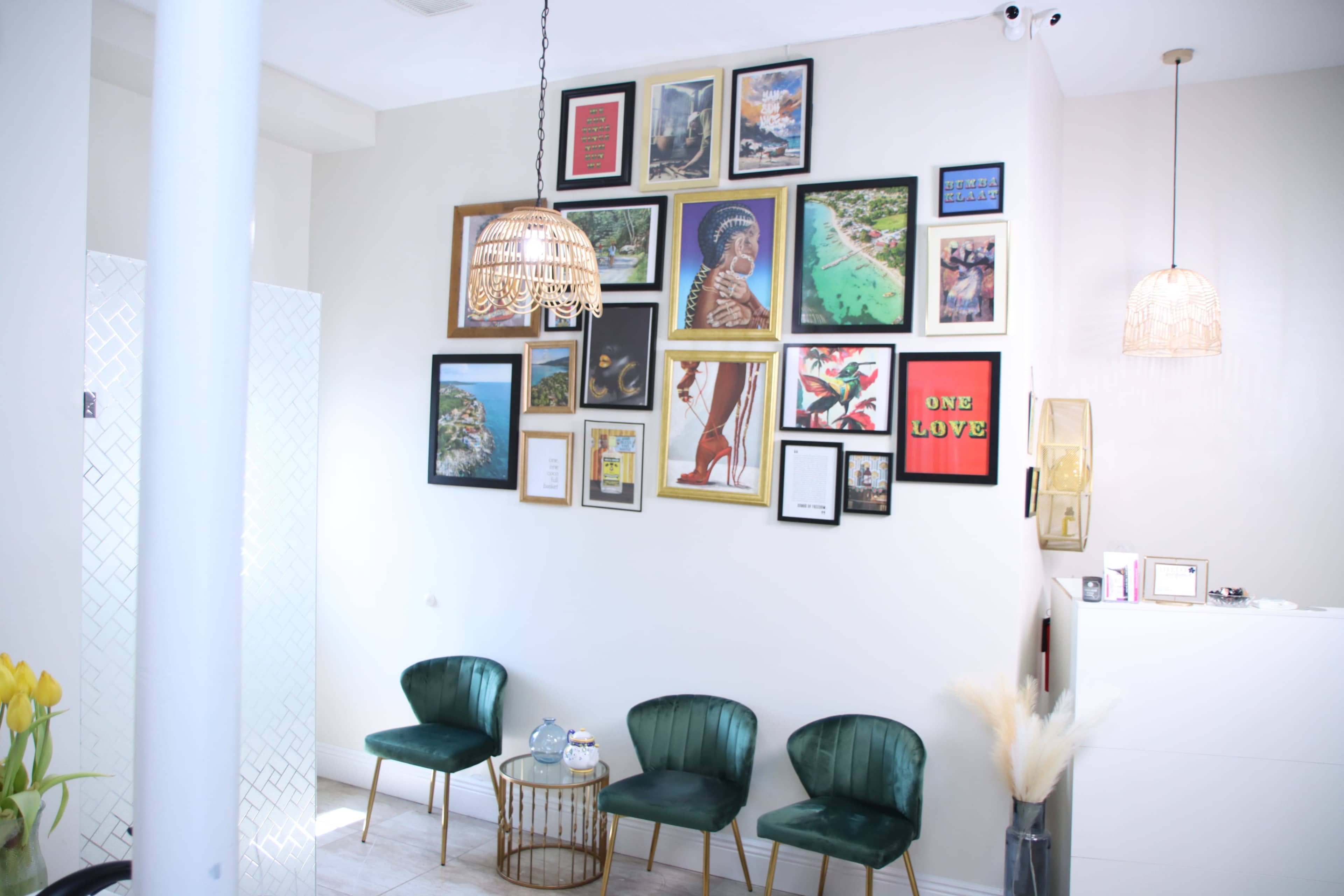 A stylish interior with a gallery wall featuring various framed artworks and photographs, accompanied by three green chairs and decorative lighting.