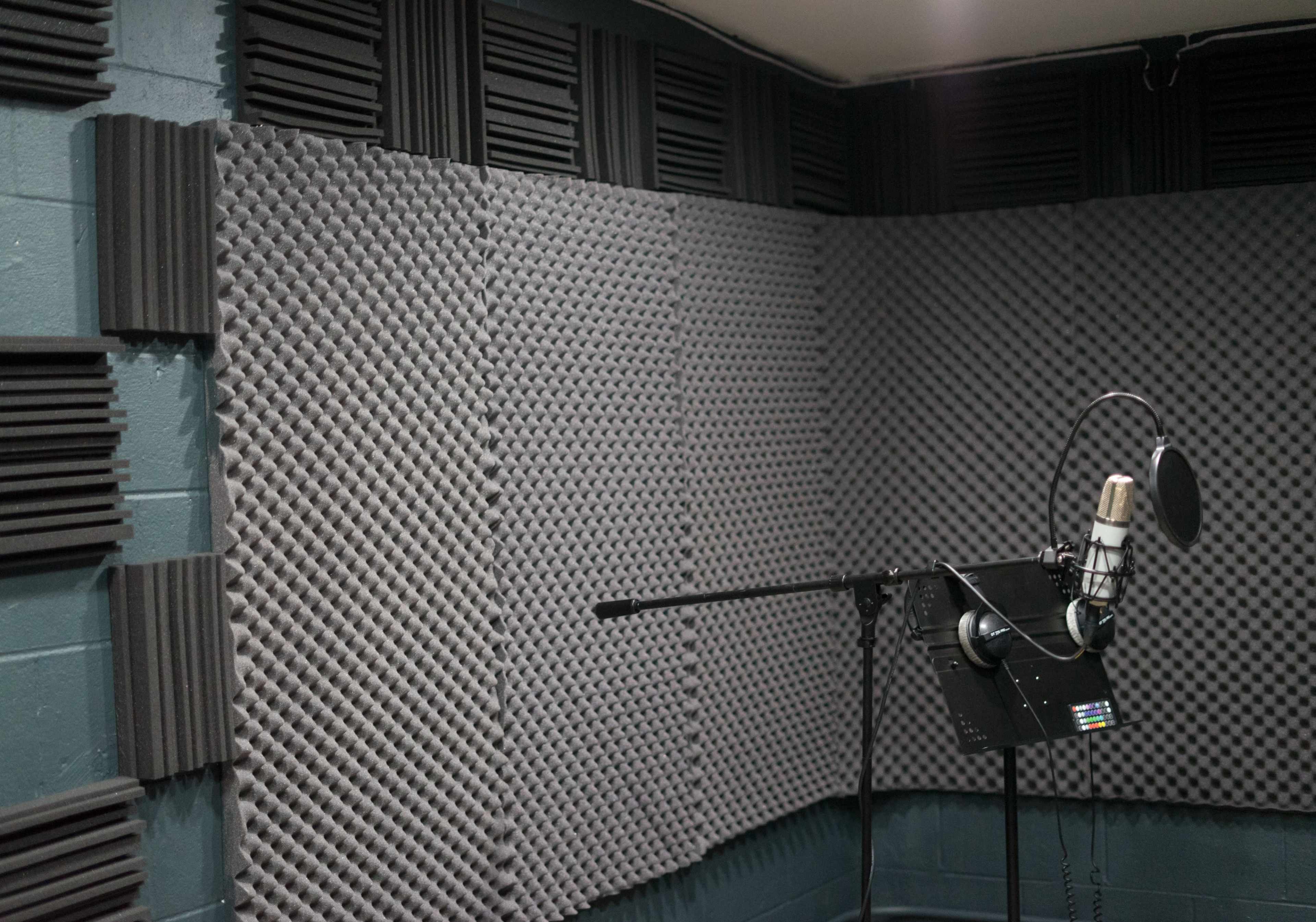 A soundproof recording studio with acoustic foam panels lining the walls and a microphone positioned on a stand.