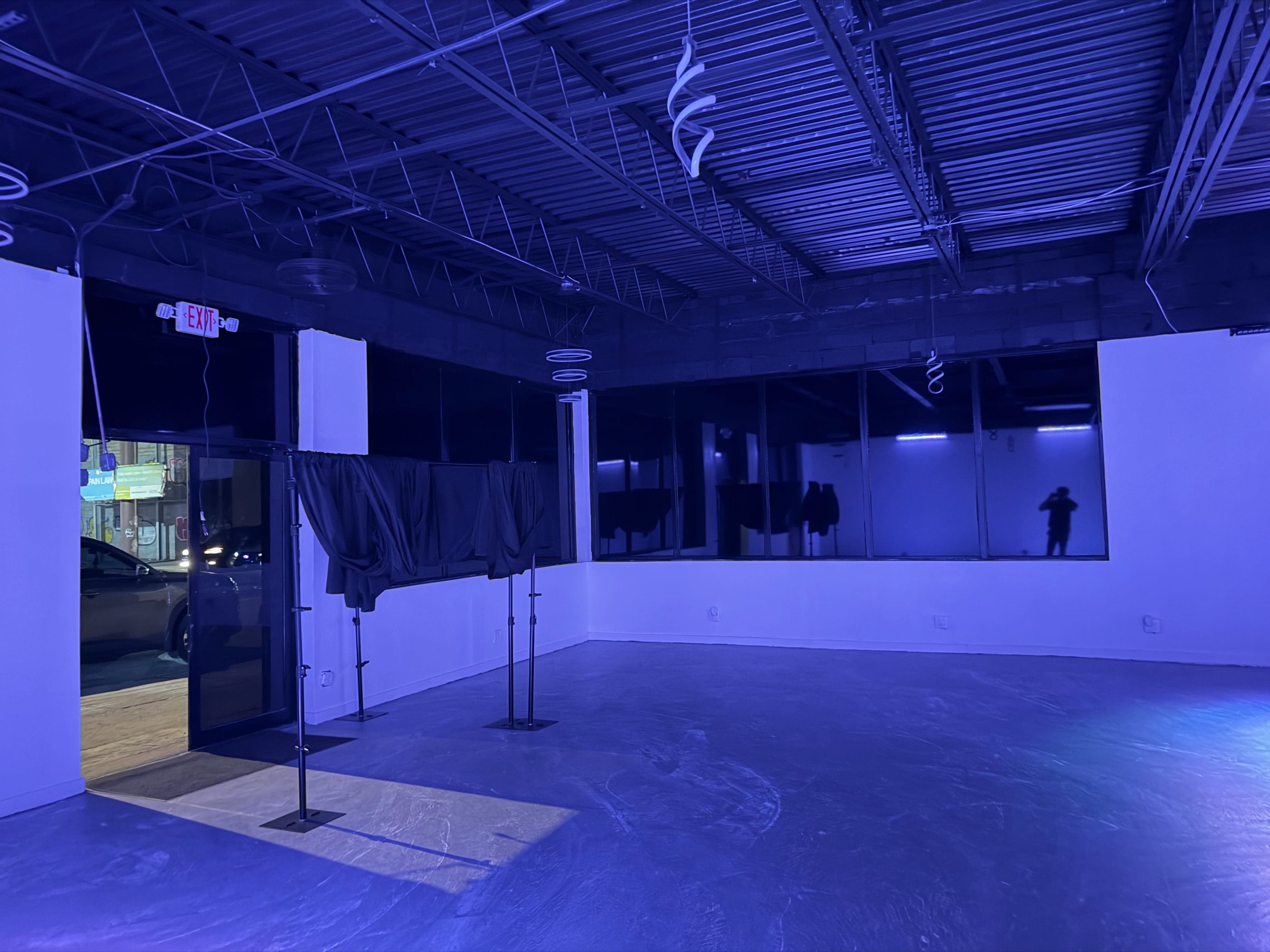 The image shows an empty room with a polished floor, dim lighting, and large windows covered by dark curtains.