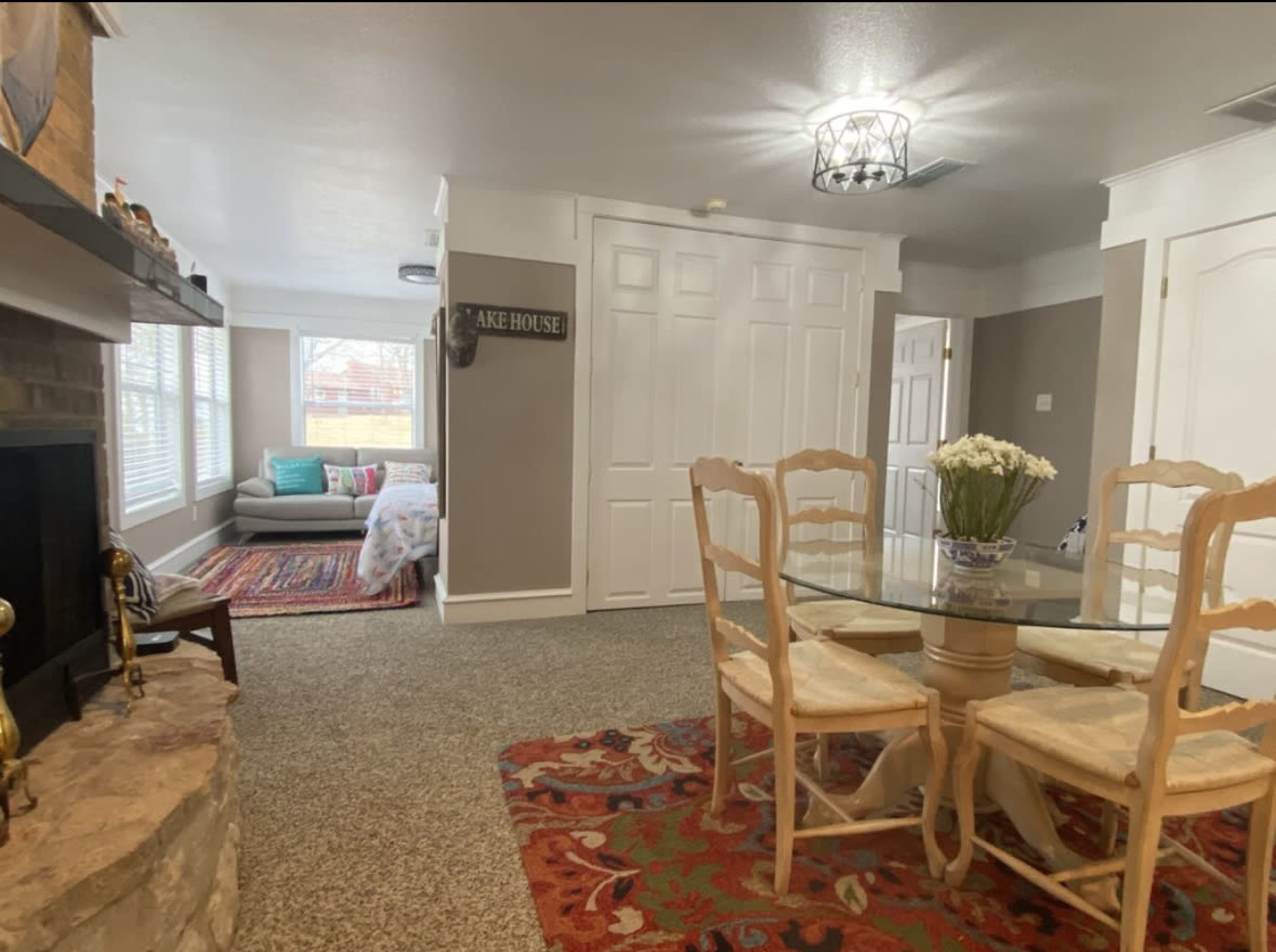 A cozy living space featuring a dining table, a stone fireplace, and a seating area with a sofa and patterned rug.
