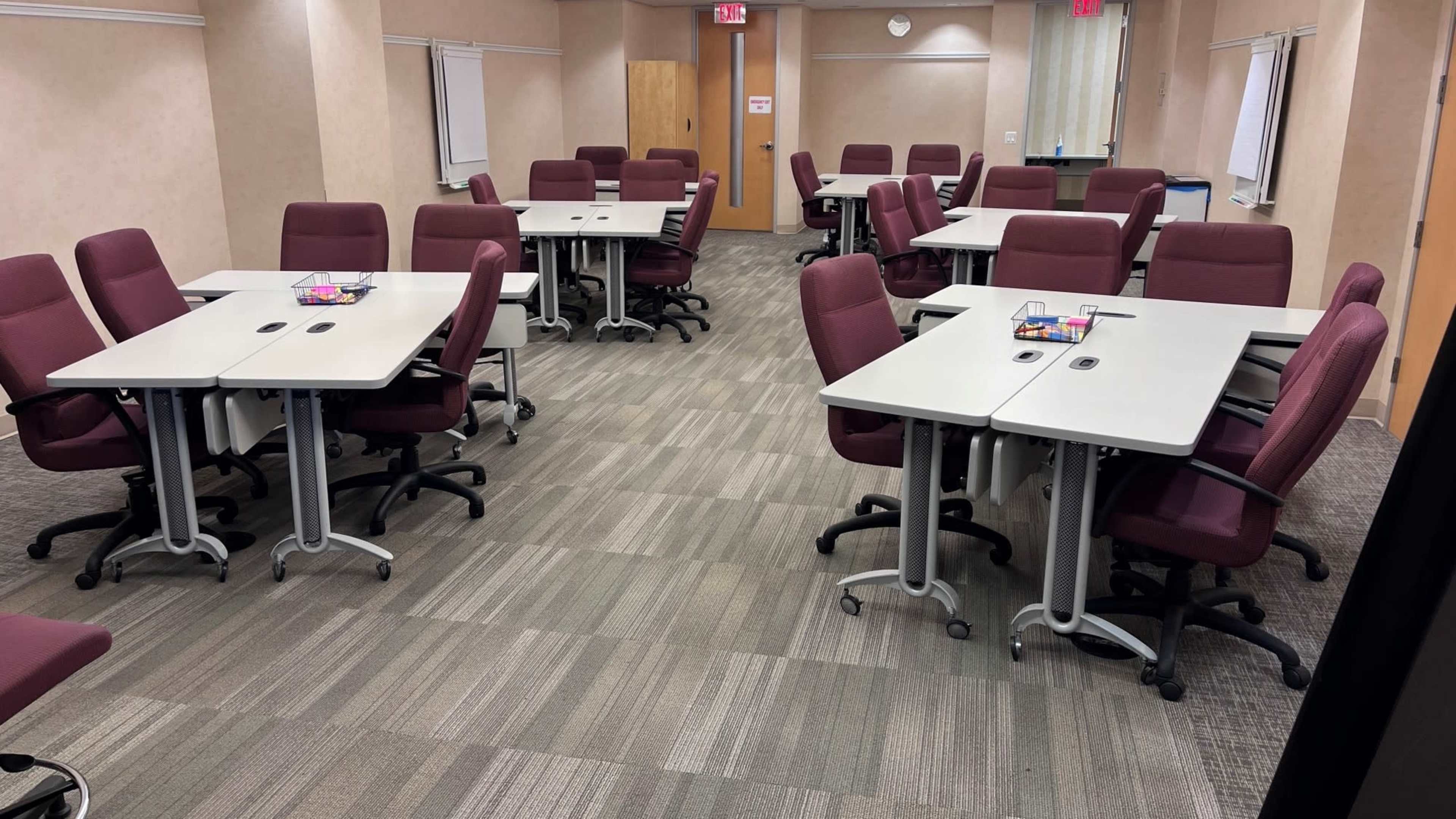 The image shows a conference room with several clusters of tables and chairs arranged in a professional layout.