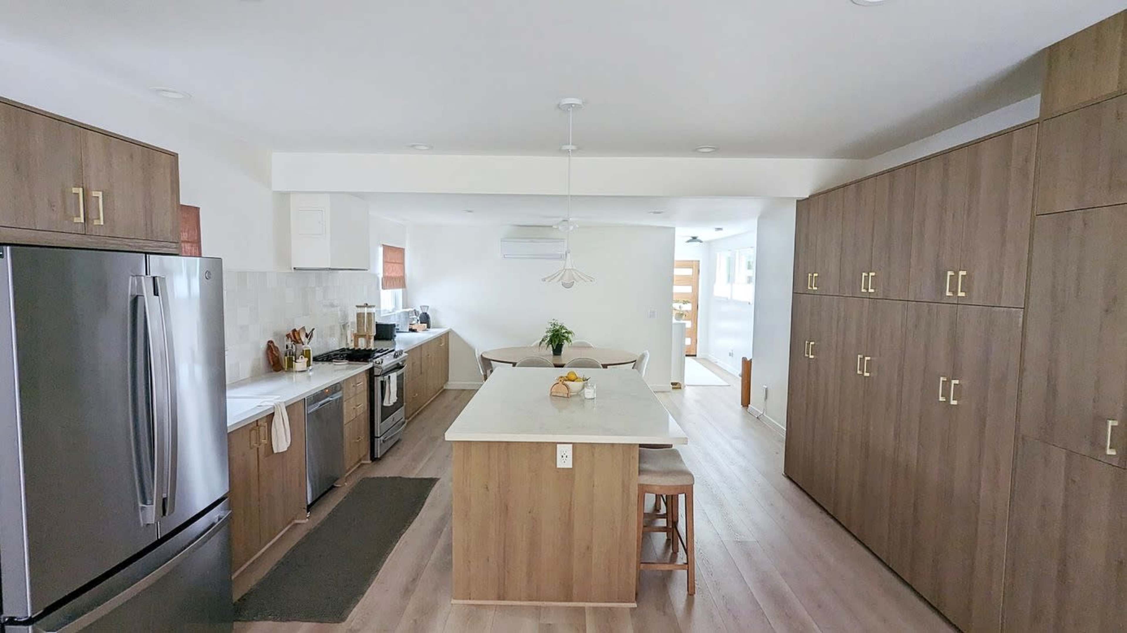 The image shows a modern kitchen with a central island, stainless steel appliances, and wooden cabinetry.