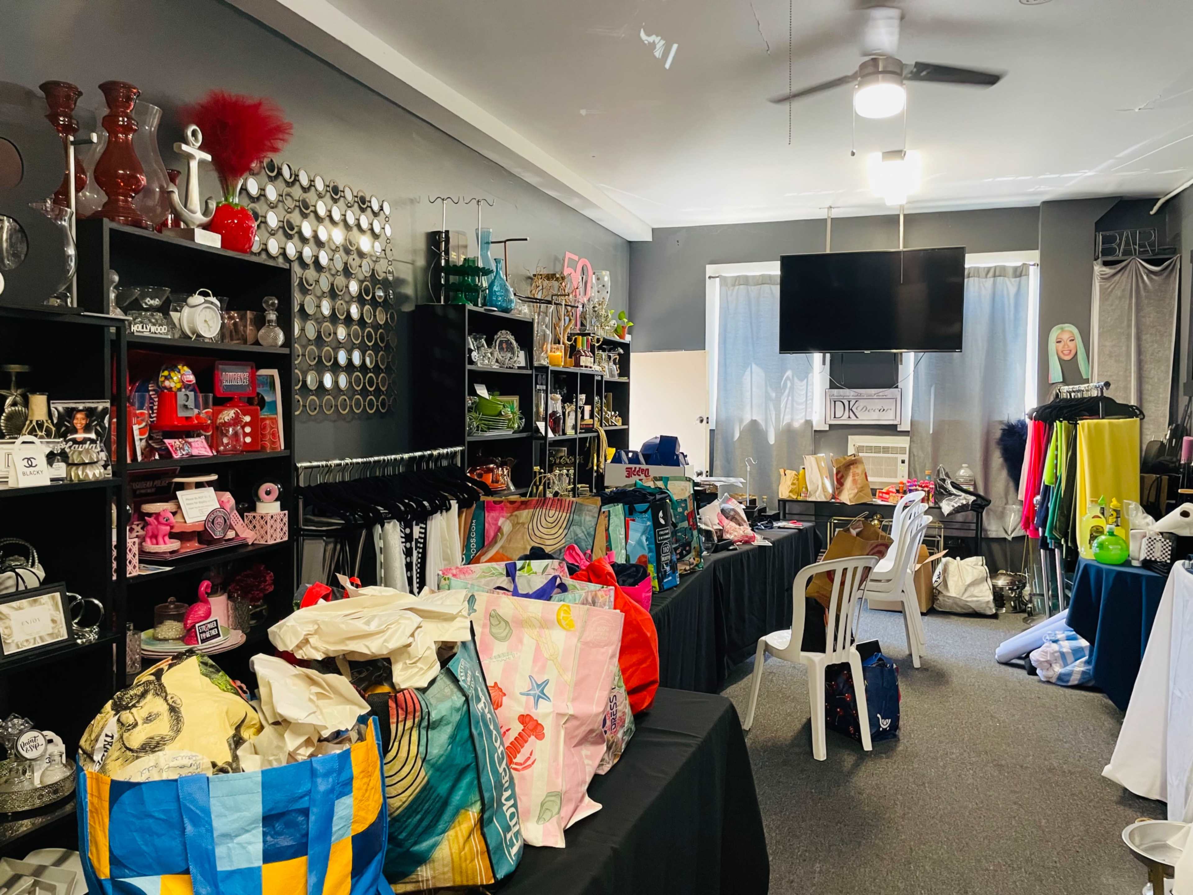 The image shows a retail space filled with various colorful bags and merchandise displayed on tables and shelves.