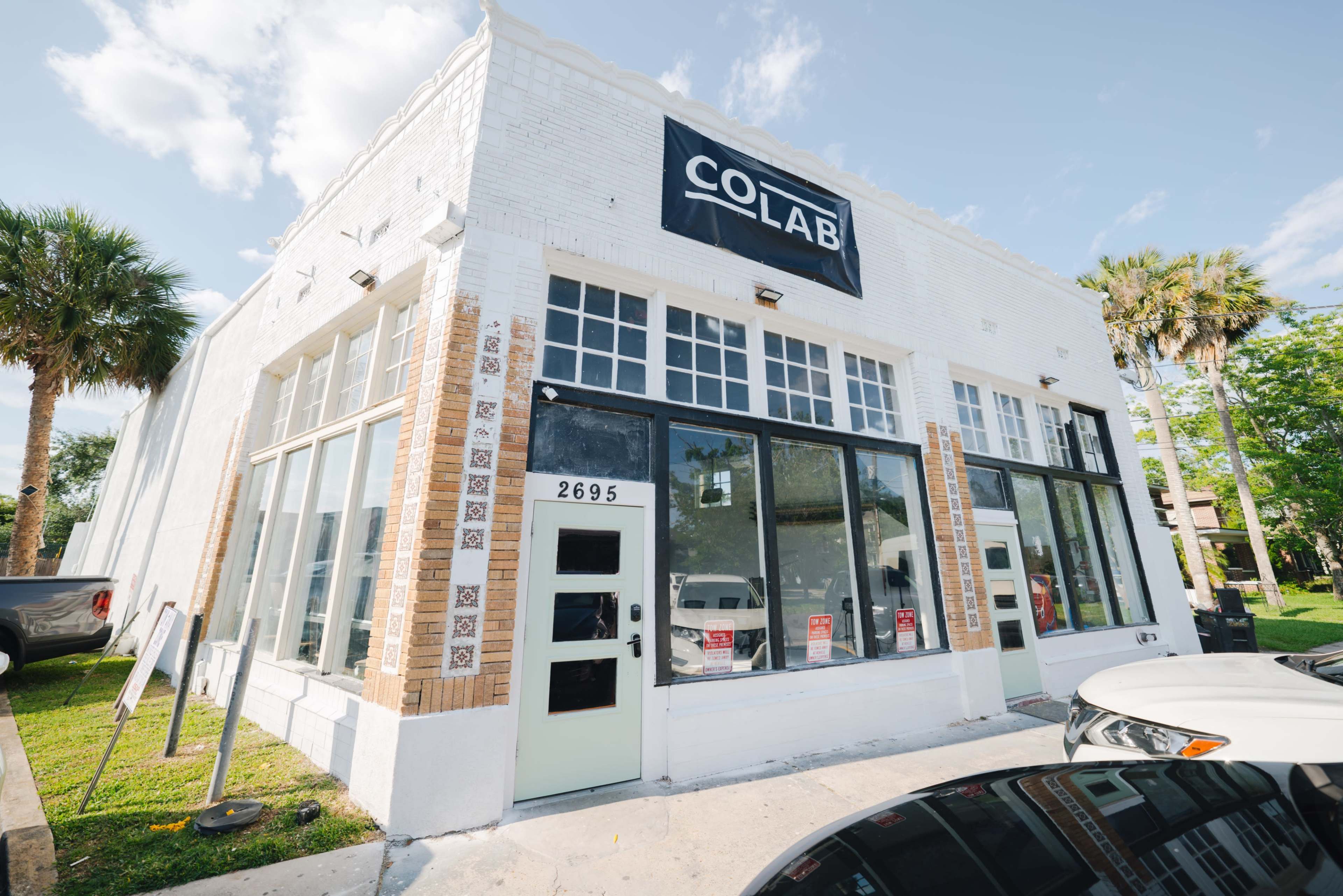 A white, two-story building with large windows and a sign reading "COLAB" on the front.