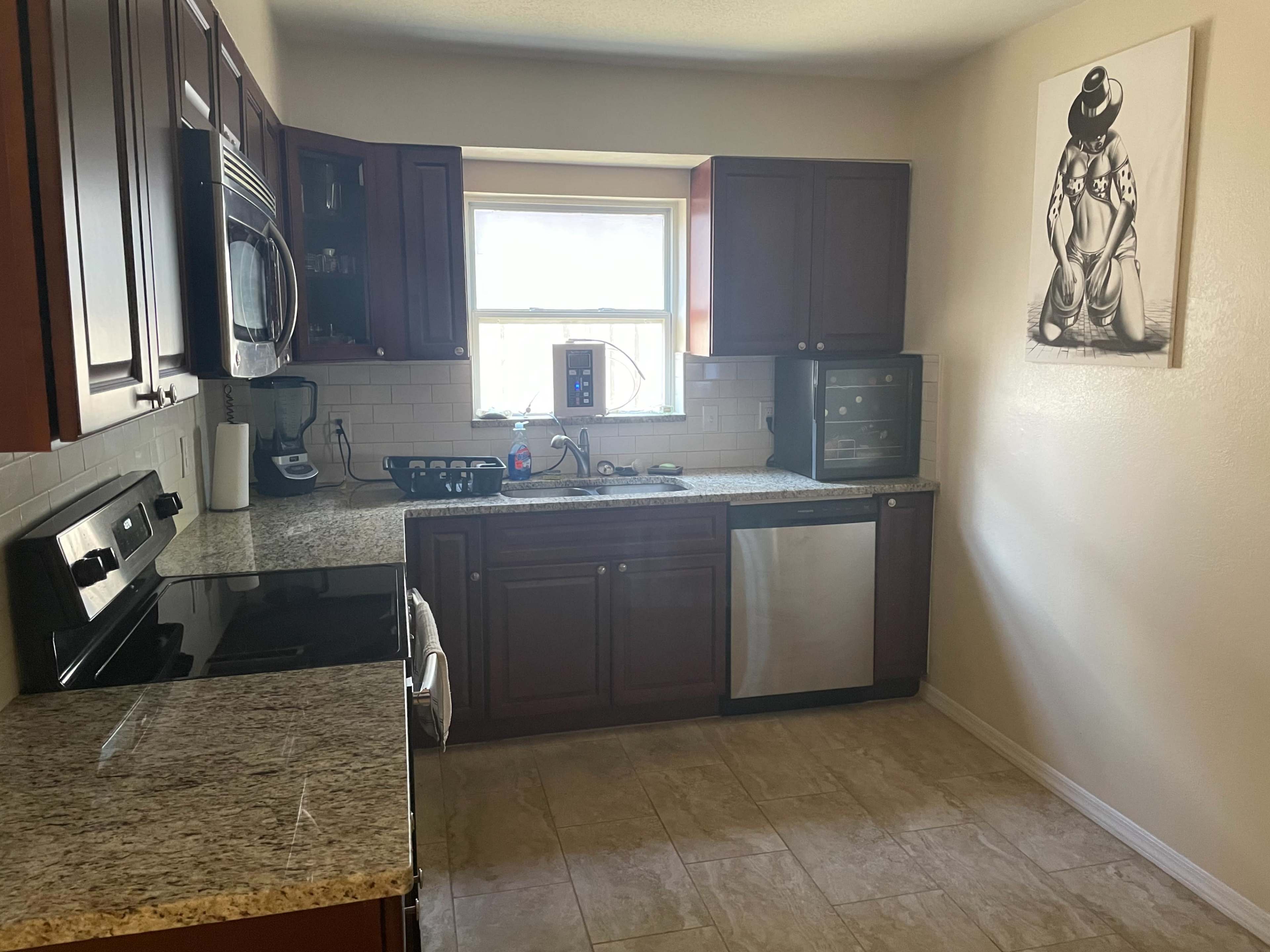 A modern kitchen features dark wooden cabinets, granite countertops, and stainless steel appliances.