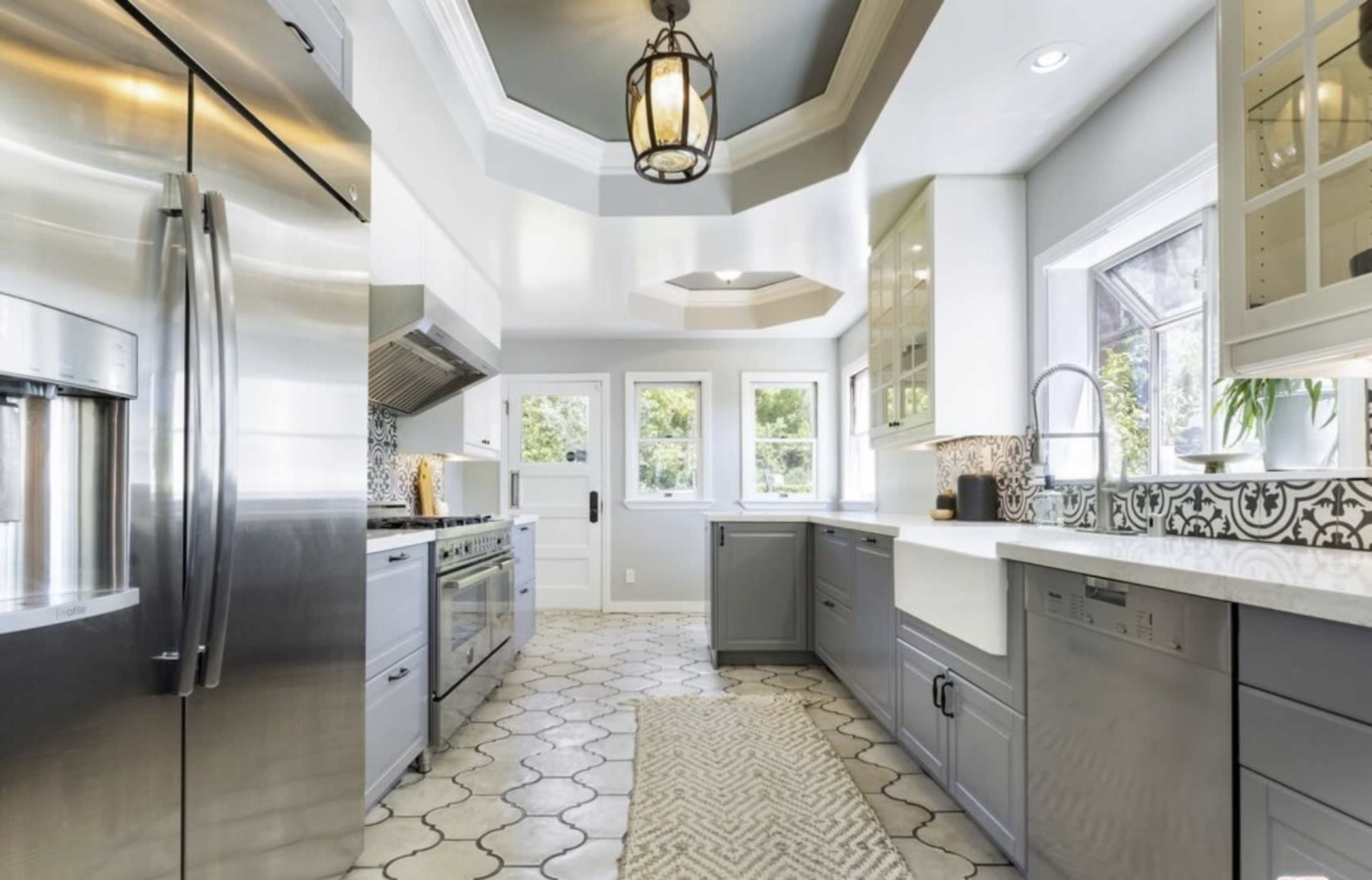 A modern kitchen features stainless steel appliances, gray cabinets, and a patterned tile backsplash.