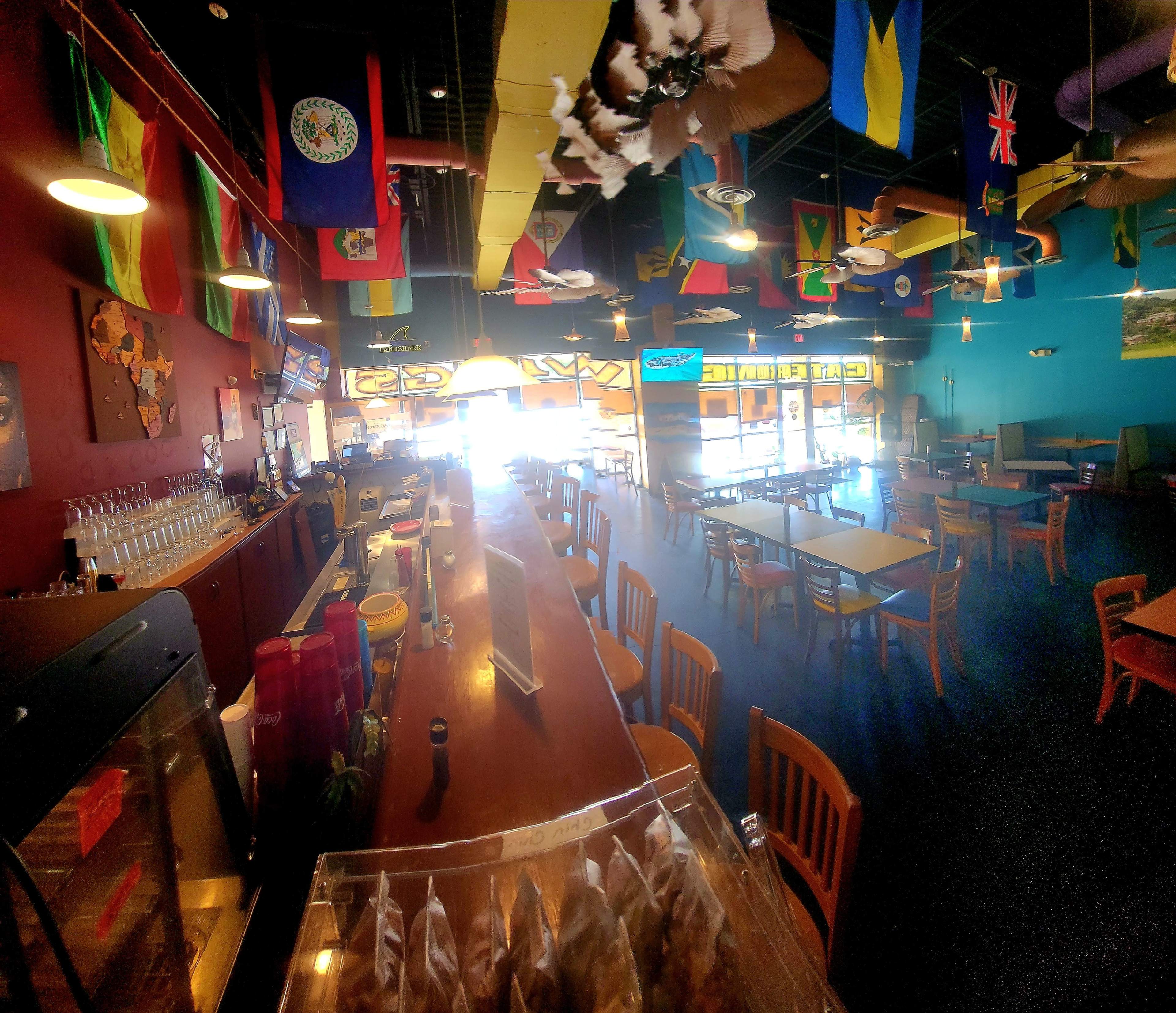 The image shows the interior of a brightly colored restaurant with various flags hanging from the ceiling and tables arranged throughout the space.